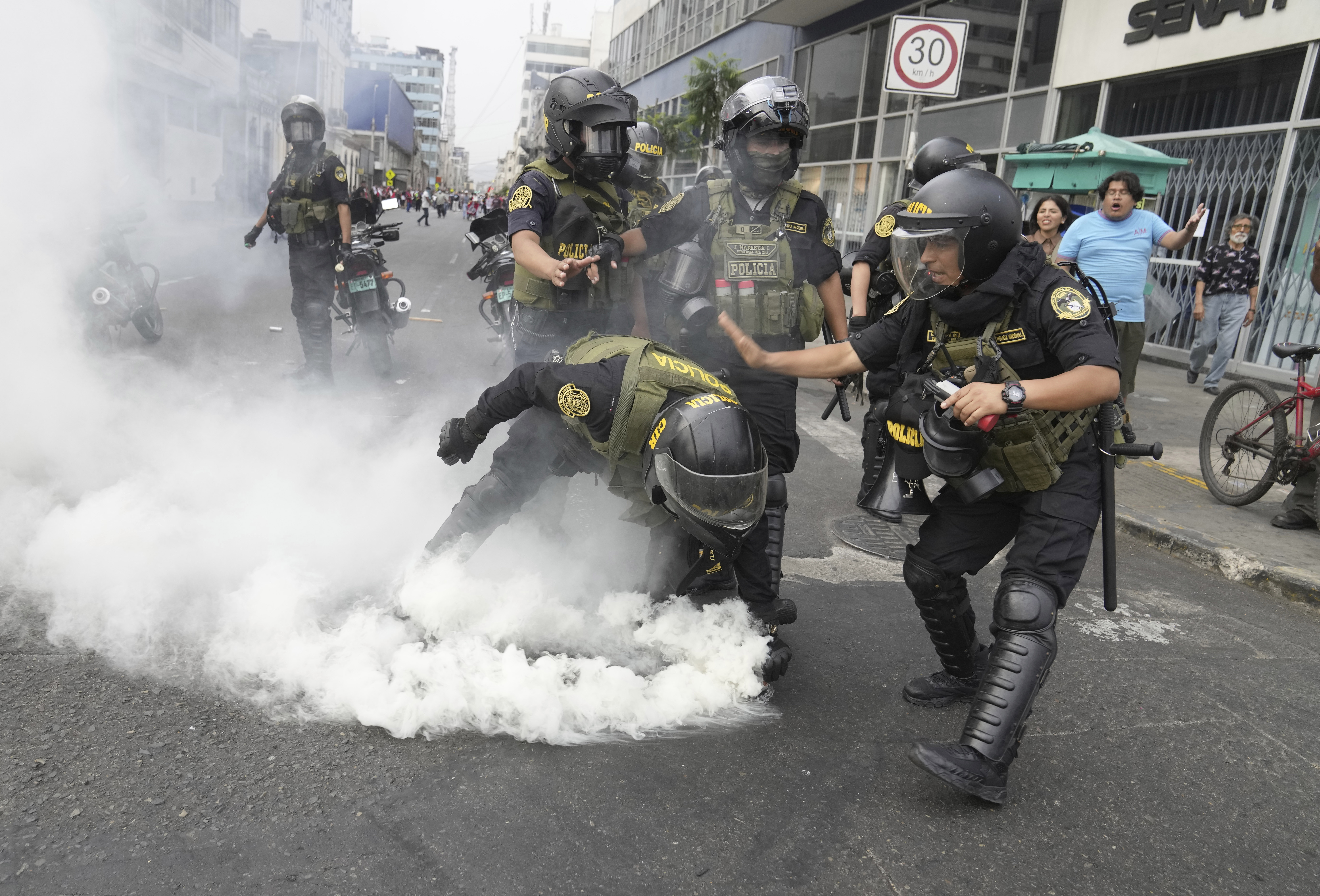 Agentes de policía recogen un bote de gas lacrimógeno que les arrojaron manifestantes antigubernamentales que viajaron a la capital desde todo el país para marchar contra la presidenta peruana Dina Boluarte en Lima, Perú, el miércoles 18 de enero de 2023. (AP Photo/Martin Mejia)