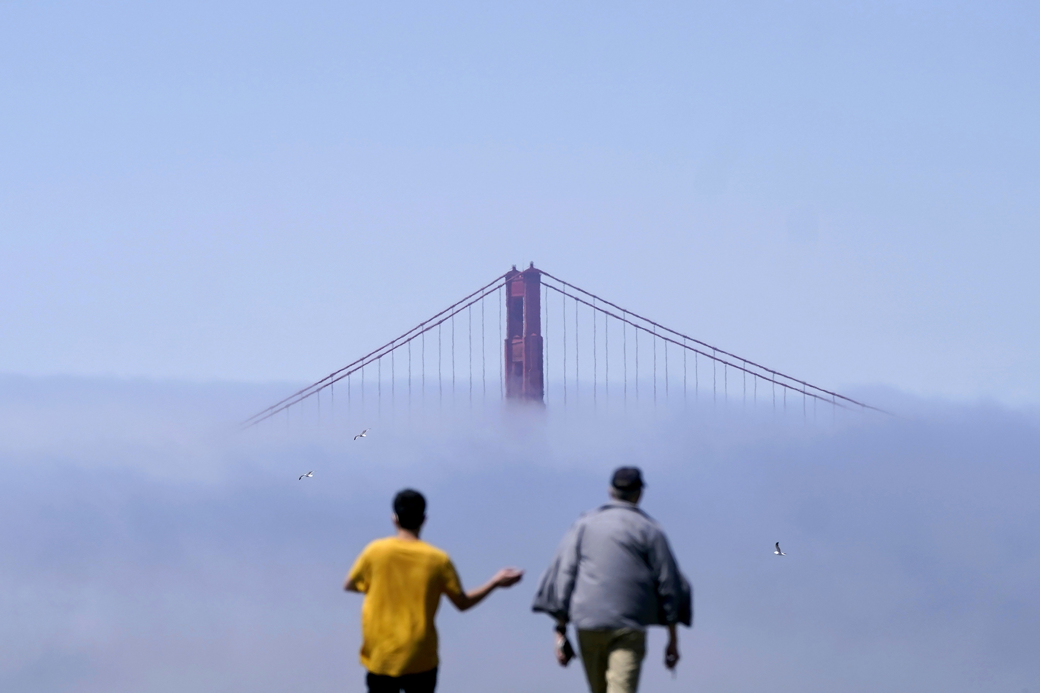 Los peatones caminan sobre una colina frente al puente Golden Gate parcialmente oscurecido por la niebla en San Francisco, el martes 16 de agosto de 2022. Foto AP/Jeff Chiu