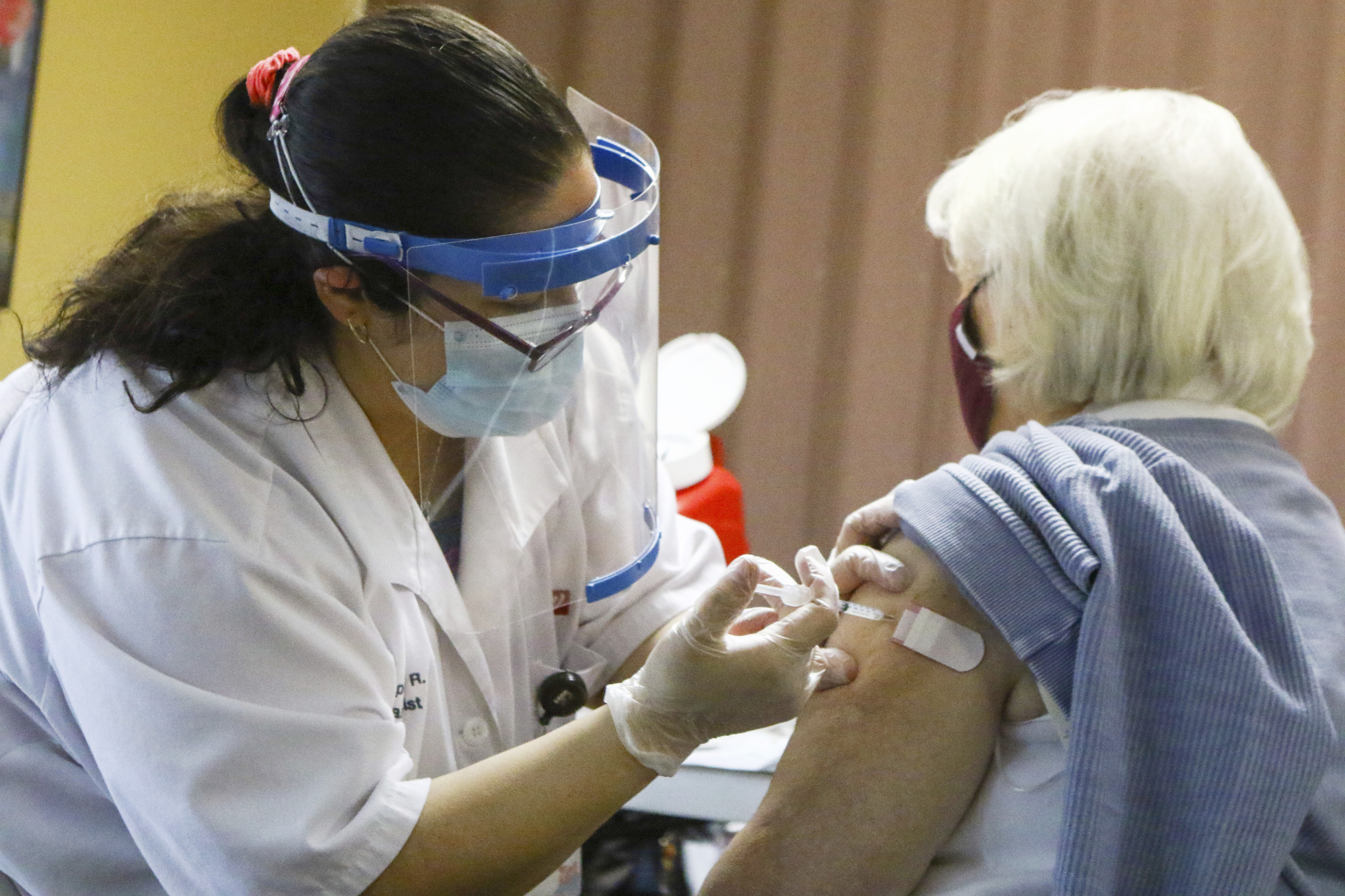 ARCHIVO - En esta fotografía de archivo un farmacéutico le da a una mujer una vacuna Moderna COVID-19 en un complejo de apartamentos en Merrillville, Indiana. (Kale Wilk / The Times vía AP, archivo)