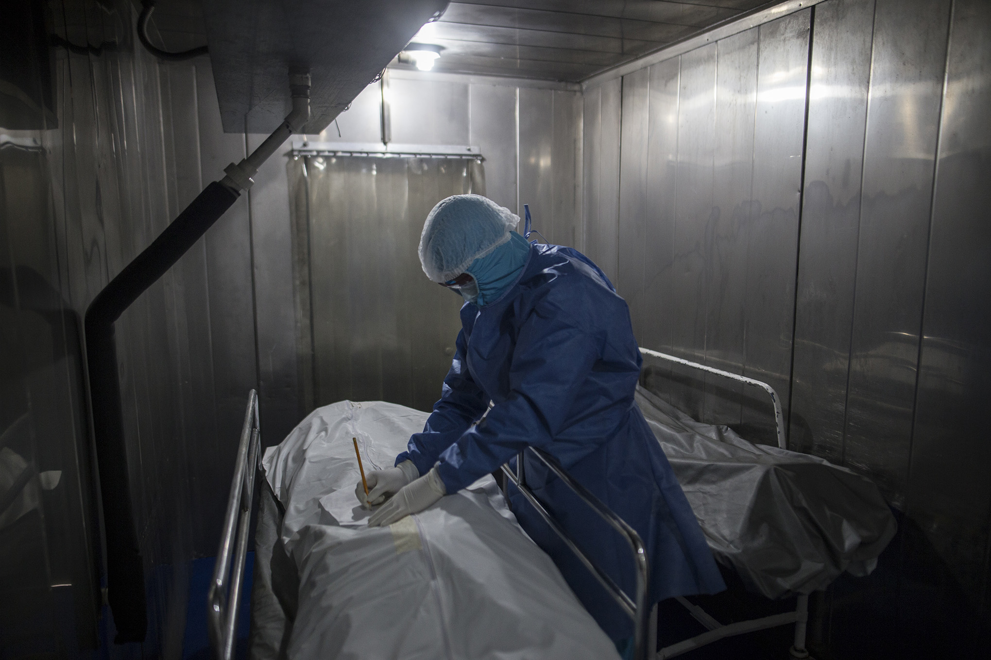 Un trabajador de la salud llena el papeleo de un paciente que murió de COVID-19, en una morgue del Hospital Samaritana en Bogotá, Colombia, el jueves 3 de junio de 2021. Colombia se ha convertido en un punto de acceso pandémico que experimenta una tercera ola de COVID-19 infecciones y aumento de muertes. (Foto AP / Ivan Valencia)