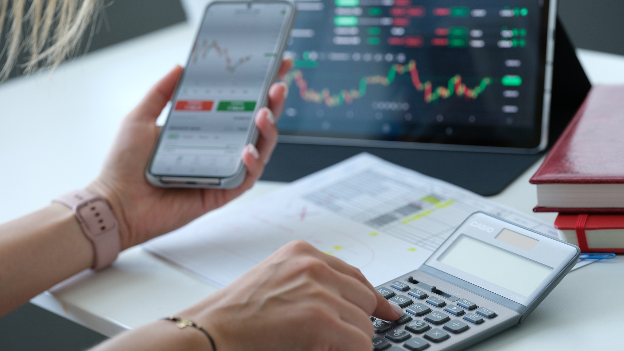 Mujer mirando el gráfico en la pantalla del teléfono móvil y contando con el primer plano de la calculadora. Concepto rentable de intercambio de criptomonedas