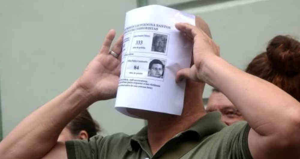 Un hombre sostiene una versión del tarjetón electoral en la que aparecen varios líderes del partido de las Farc y la suma de condenas a prisión que habían recibido antes del acuerdo de La Habana.