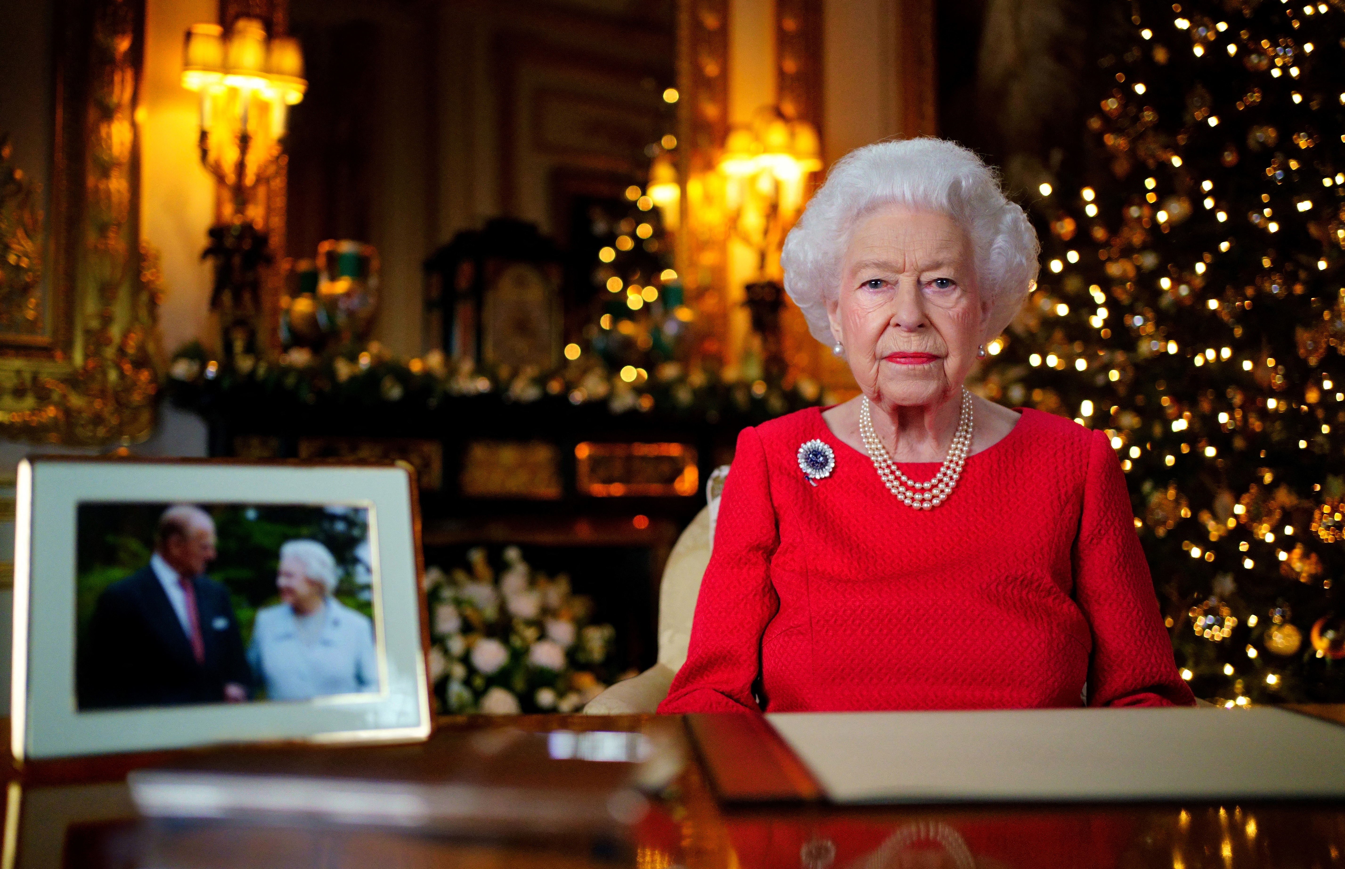 Una imagen publicada el 23 de diciembre de 2021 muestra a la reina Isabel II de Gran Bretaña posando para una fotografía mientras grababa su mensaje anual del día de Navidad, con una fotografía de ella y de su difunto esposo, el príncipe Felipe de Gran Bretaña, duque de Edimburgo, tomada en 2007 en Broadlands, para marcan su aniversario de bodas de diamantes, en el White Drawing Room del Castillo de Windsor, al oeste de Londres. (Photo by Victoria Jones / POOL / AFP) / EMBARGOED UNTIL 2230 GMT on December 23, 2021.