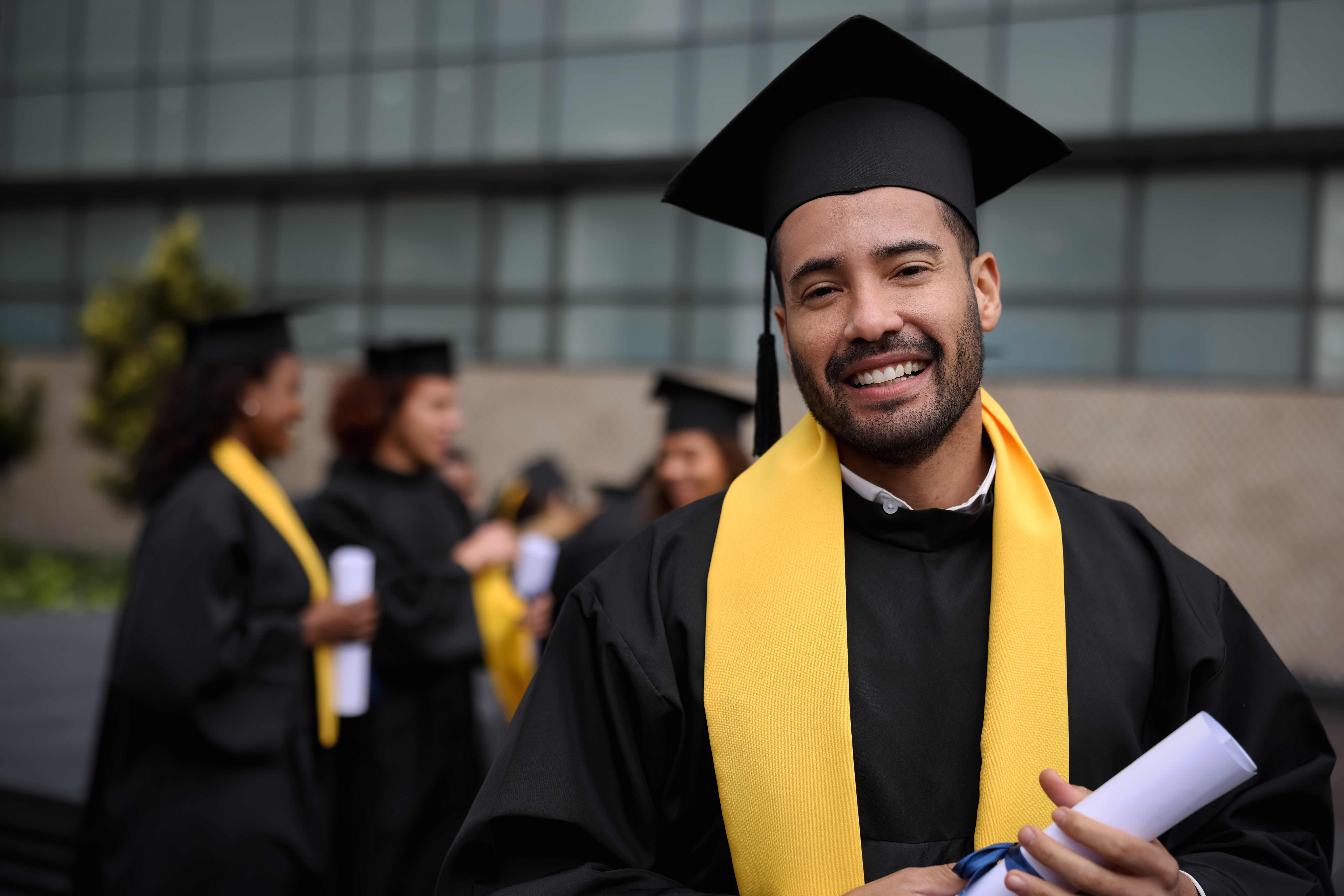 Retrato de un estudiante de posgrado feliz sosteniendo su diploma el día de la graduación y mirando a la cámara sonriendo - conceptos de educación