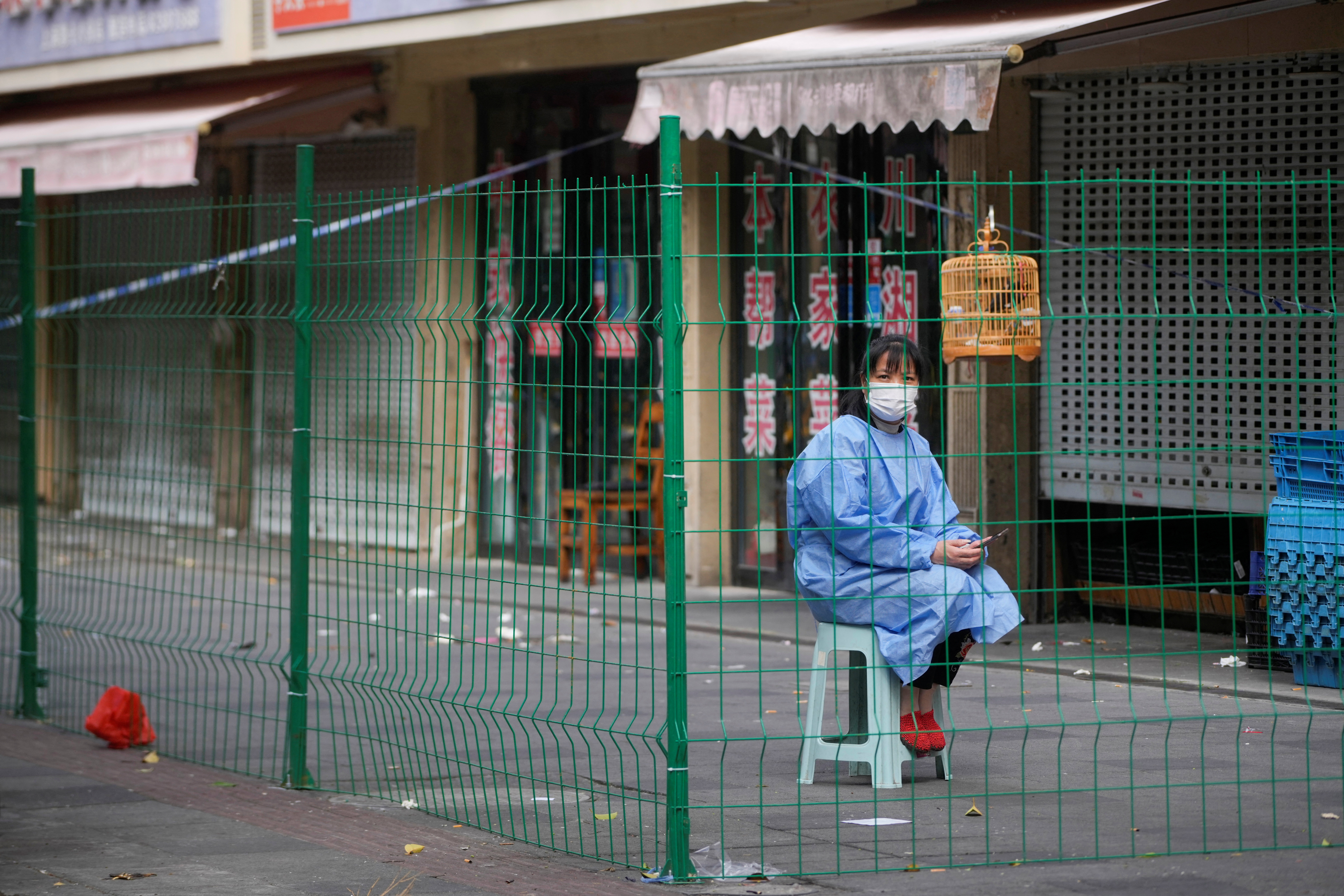Un trabajador con traje de protección se sienta detrás de una barrera en una zona sellada tras el brote de la enfermedad por coronavirus (COVID-19), en Shanghái, China, el 11 de octubre de 2022. REUTERS/Aly Song
