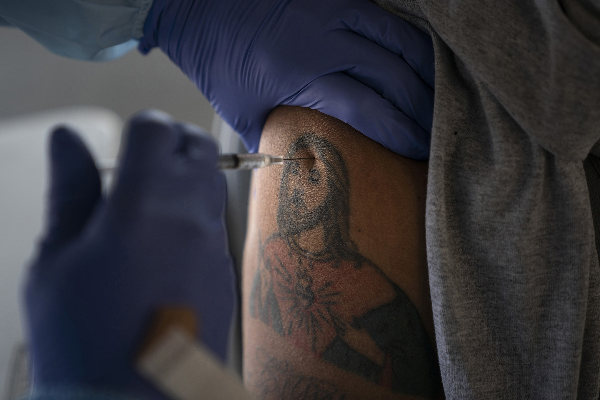 El trabajador agrícola Jorge Americano recibe la vacuna Pfizer-BioNTech COVID-19 en su brazo con un tatuaje que representa a Jesús en Tudor Ranch en Mecca, California, el jueves 21 de enero de 2021 (AP Photo / Jae C. Hong)