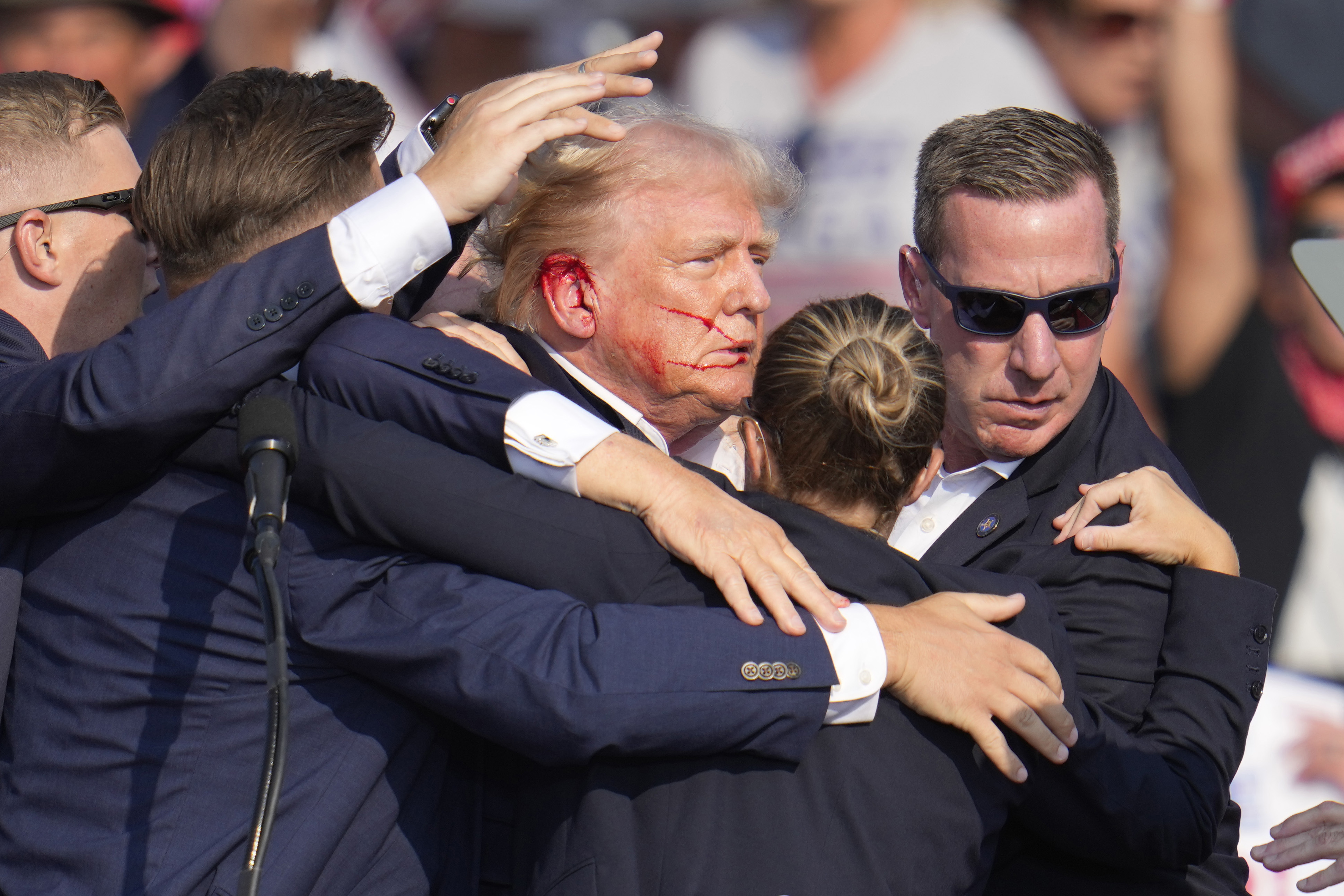 Republican presidential candidate former President Donald Trump is helped off the stage at a campaign event in Butler, Pa., on Saturday, July 13, 2024. (AP Photo/Gene J. Puskar)