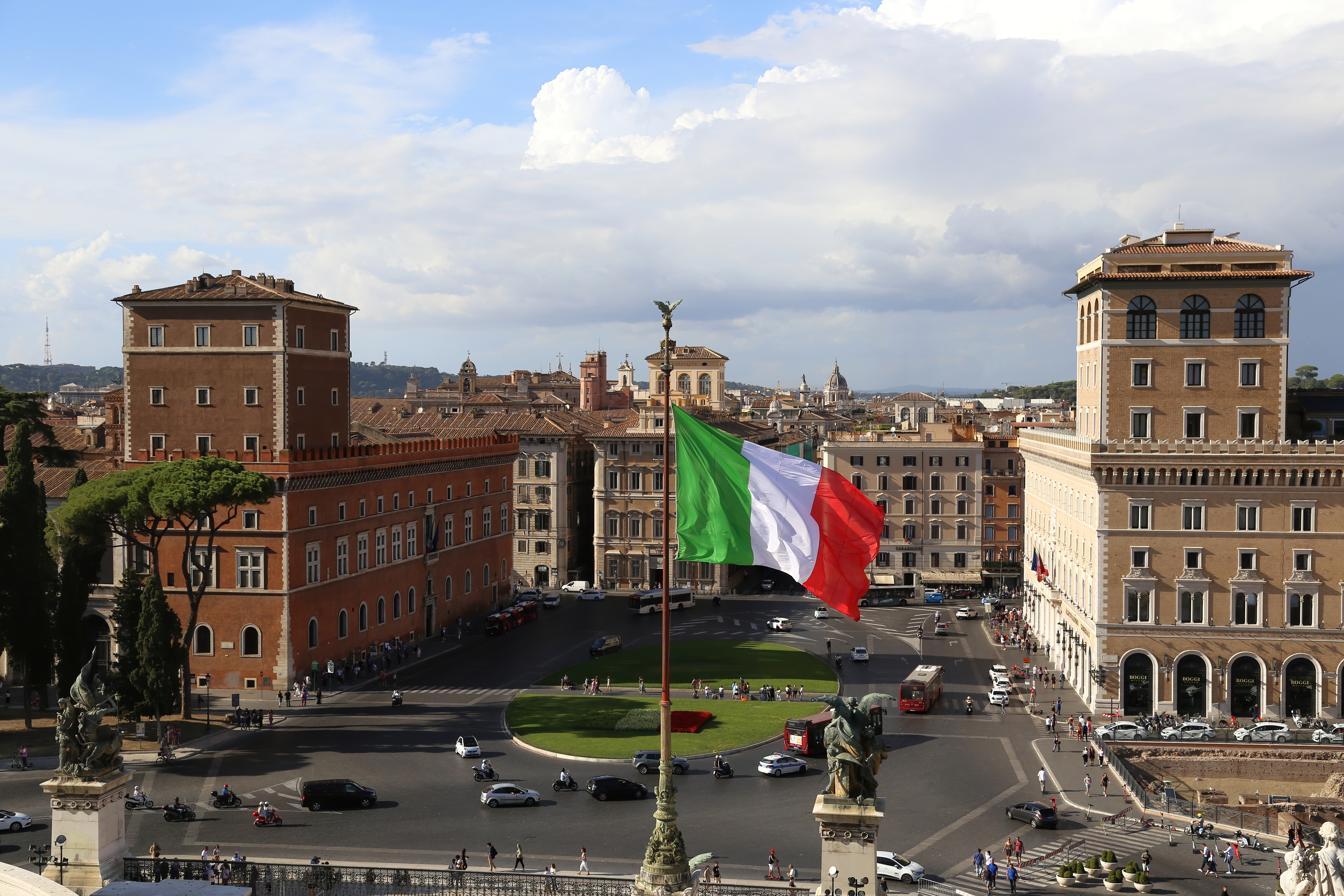 Roma, Italia. Una gran bandera italiana ondea sobre el monumento Altar de la Patria, también conocido como Vittoriano, frente a la Piazza Venezia en un día soleado