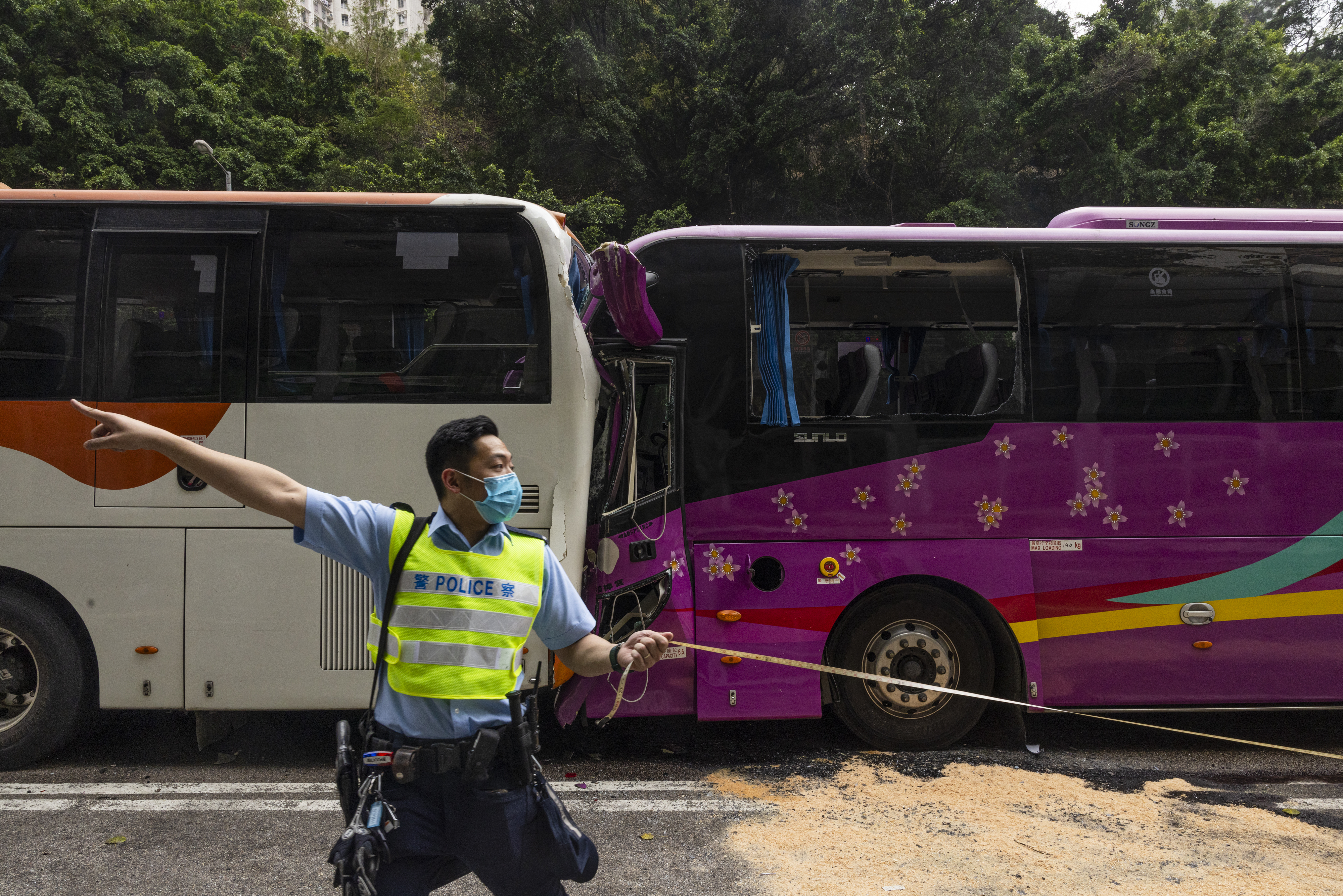 Un oficial de policía inspecciona después de un accidente en una carretera en Hong Kong, el viernes 24 de marzo de 2023. Cuatro autobuses de pasajeros y un camión chocaron el viernes cerca de un túnel de carretera de Hong Kong, hiriendo a decenas de personas. (AP Photo/Louise Delmotte)