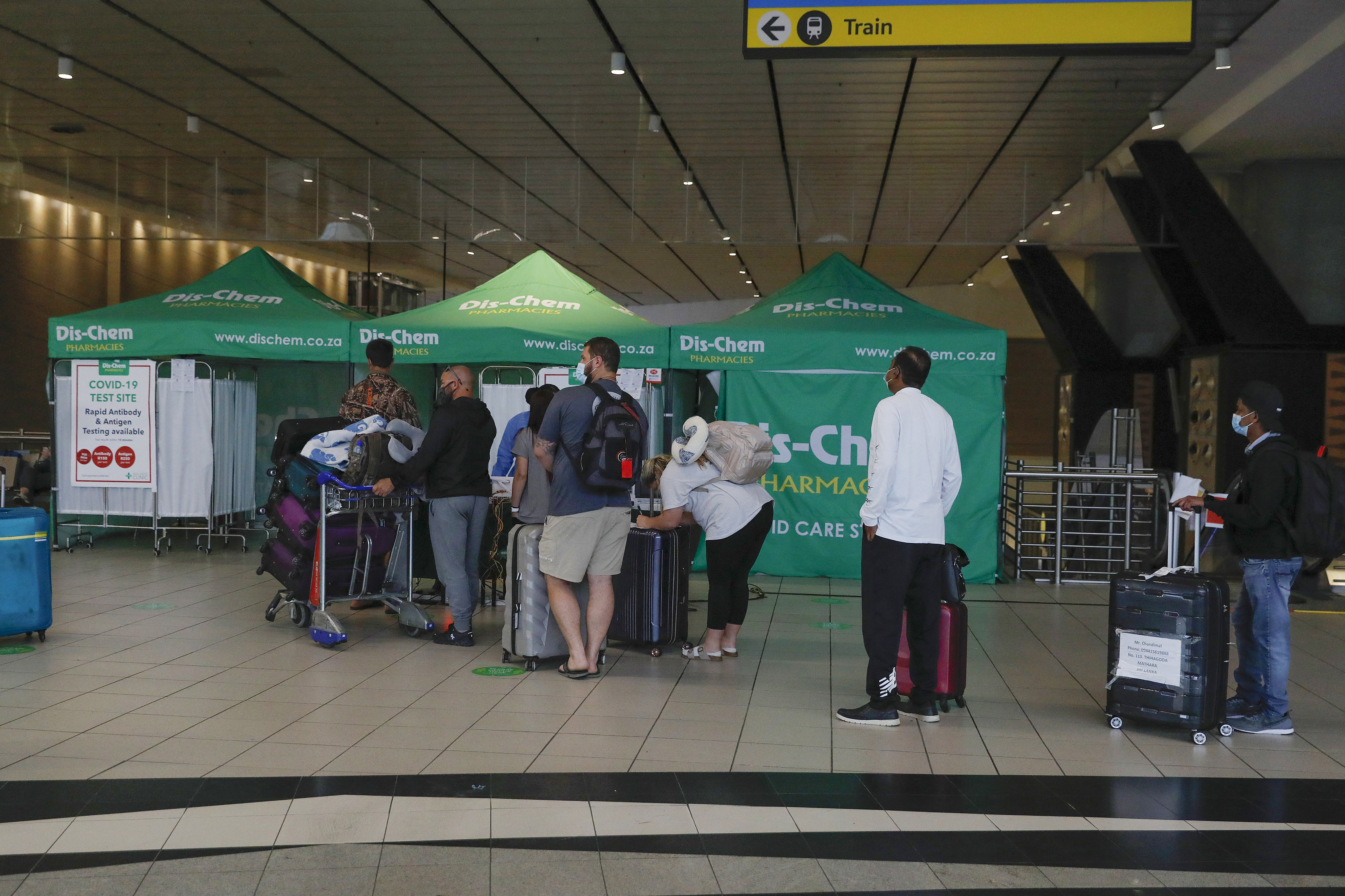 Travellers queue at an area for polymerase chain reaction (PCR) Covid-19 tests at OR Tambo International Airport in Johannesburg on November 27, 2021, after several countries banned flights from South Africa following the discovery of a new Covid-19 variant Omicron. - A flurry of countries around the world have banned ban flights from southern Africa following the discovery of the variant, including the United States, Canada, Australia,Thailand, Brazil and several European countries. The main countries targeted by the shutdown include South Africa, Botswana, eSwatini (Swaziland), Lesotho, Namibia, Zambia, Mozambique, Malawi and Zimbabwe. (Photo by Phill Magakoe / AFP)