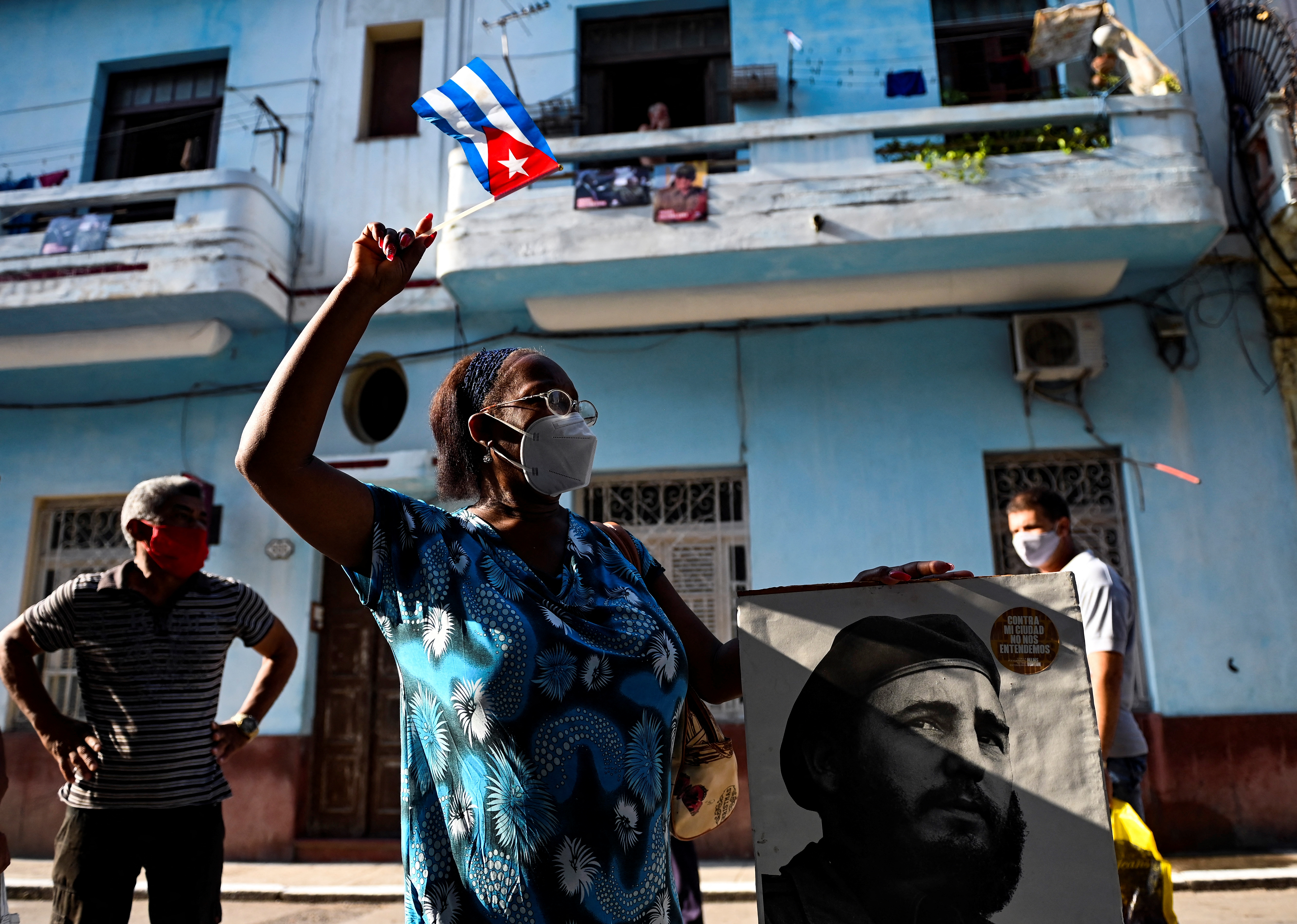 An elderly woman waves a Cuban flag holding a poster of Cuban late leader Fidel Castro in Havana, on July 26, 2021. - The Cuban government on July 26 will commemorate the 68th anniversary of the guerrilla assault on the Moncada Barracks, widely regarded as the beginning of the Cuban Revolution. (Photo by YAMIL LAGE / AFP)