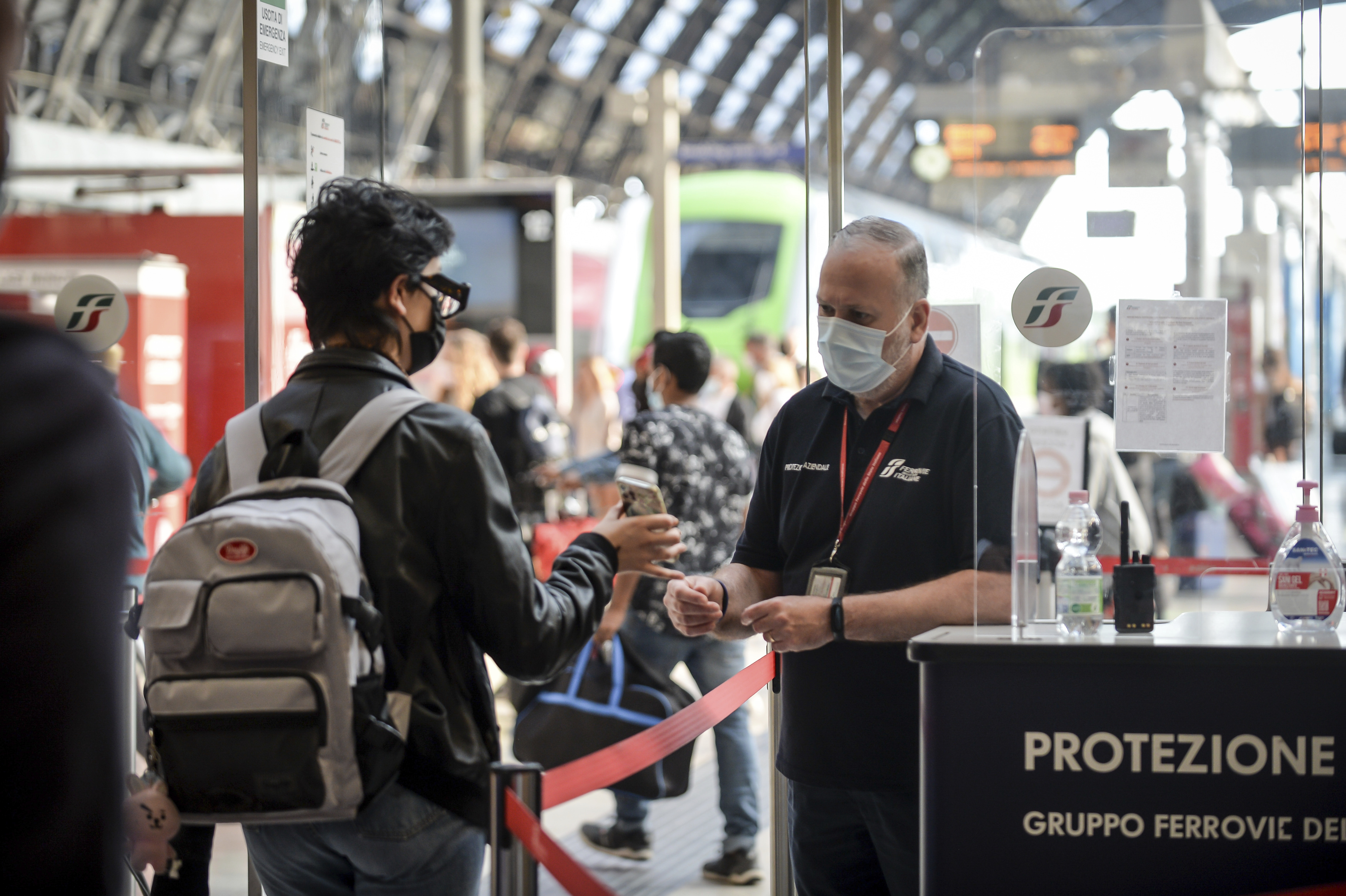 Un pasajero sostiene su teléfono en un punto de control en la estación de tren Stazione Centrale de Milán, Italia. (Claudio Furlan / LaPresse vía AP)
