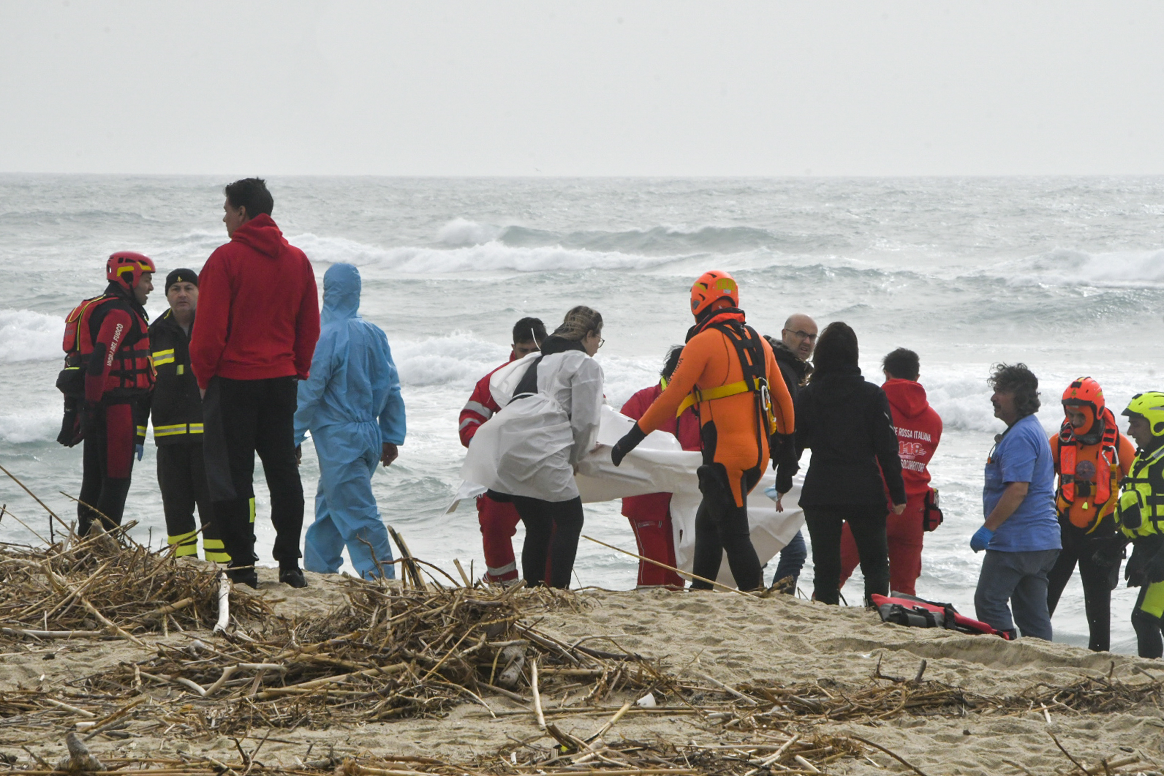 Rescatistas recuperan un cadáver de una playa cercana a Cutro, en el sur de Italia, el domingo 26 de febrero de 2023, después de que un bote de migrantes se partiera en un mar picado.