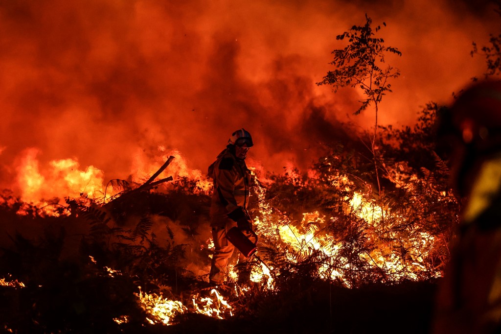 Los bomberos intentan evitar que el incendio forestal se propague debido al cambio de viento, mientras luchan contra un incendio forestal cerca de Louchats en Gironde, suroeste de Francia el 17 de julio de 2022 (Foto de THIBAUD MORITZ / AFP)