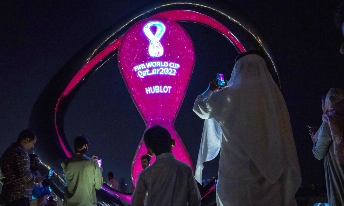 People take photos with the official FIFA World Cup Countdown Clock on Doha's corniche, in Qatar, Friday, Oct. 14, 2022. (AP/Nariman El-Mofty)