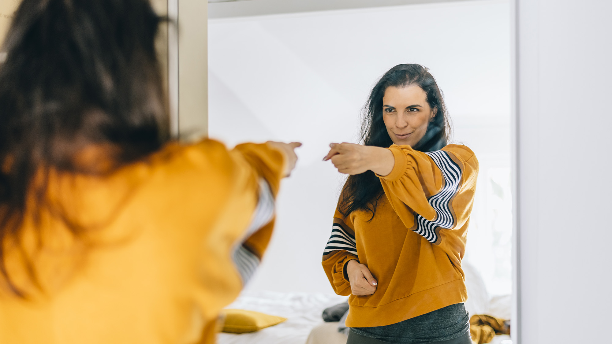 Mujer soltera segura de sí misma señalando con el dedo su reflejo en el espejo, bailando y sintiéndose bien. Persona independiente con autoestima alta habla positivo y lo puedo hacer motivacion. Madre satisfecha en los años 40 amada inspirada y orgullosa.