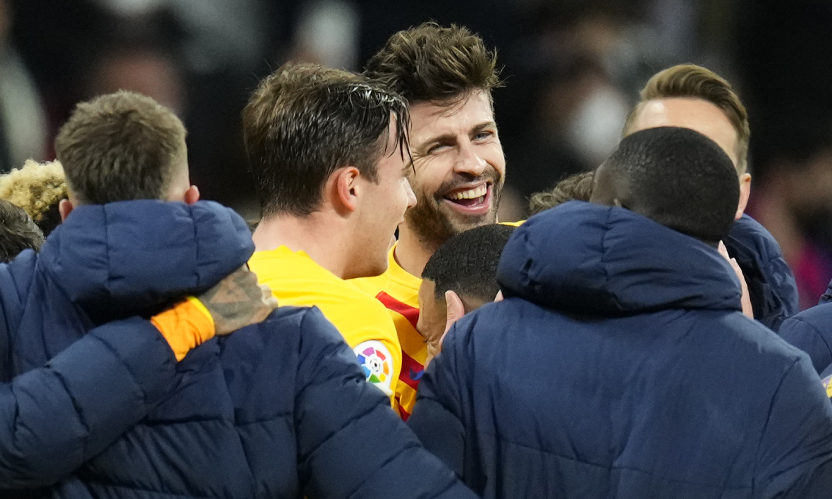 Gerard Piqué (centro, de frente) festeja con sus compañeros la goleada 4-0 de Barcelona al Real Madrid en la liga española el 20 de marzo del 2022 en el estadio Santiago Bernabéu de Madrid. (AP Photo/Manu Fernández)