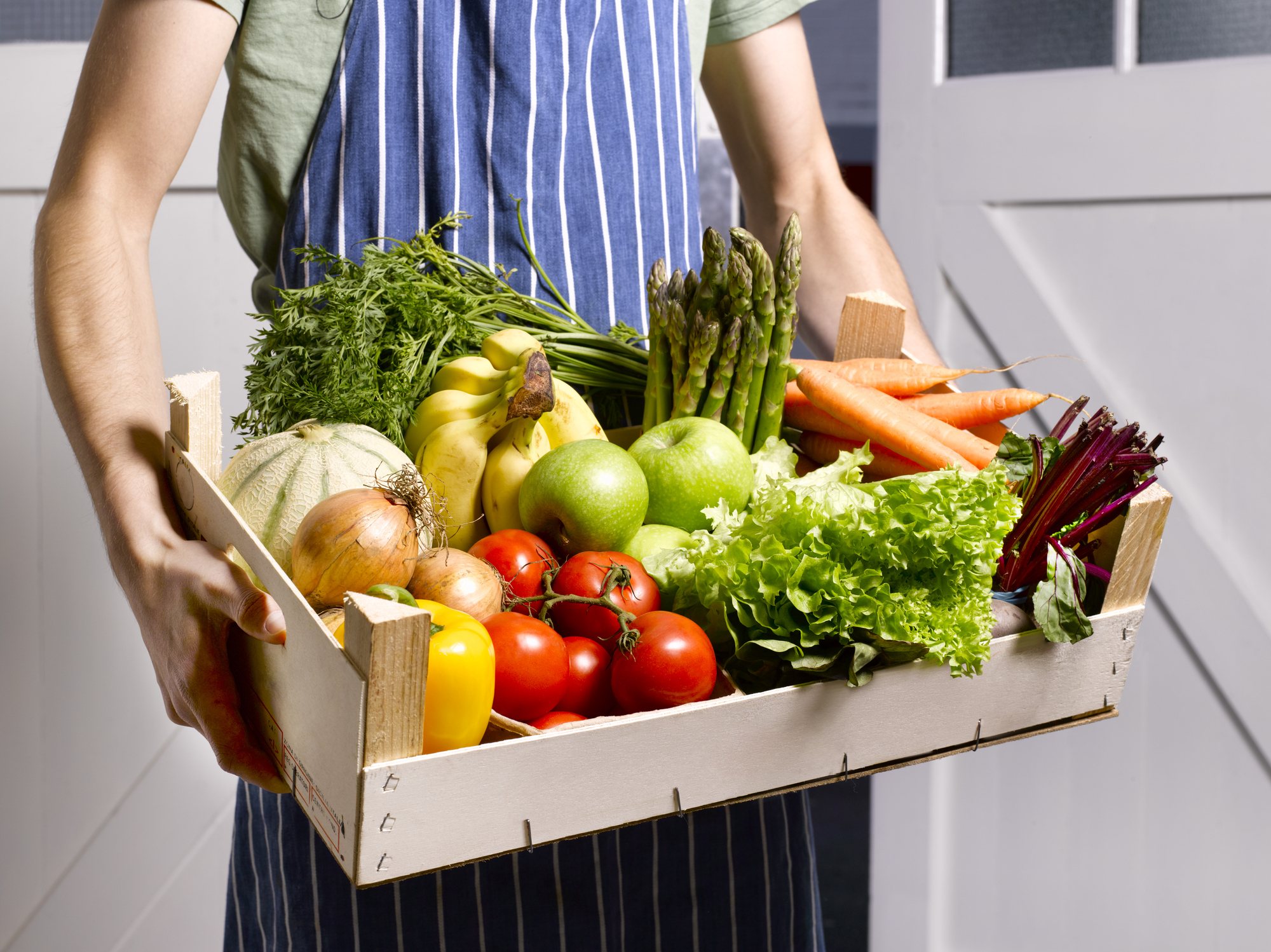 Hombre entregando caja de frutas y verduras