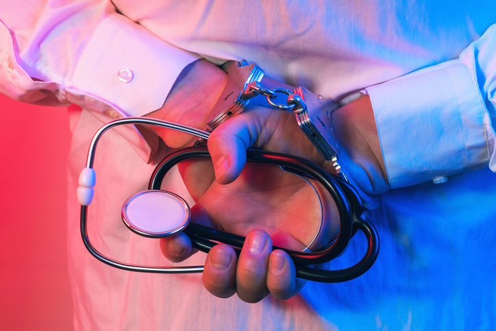Doctor in handcuffs with a statoscope in his hands, the concept of arresting a doctor