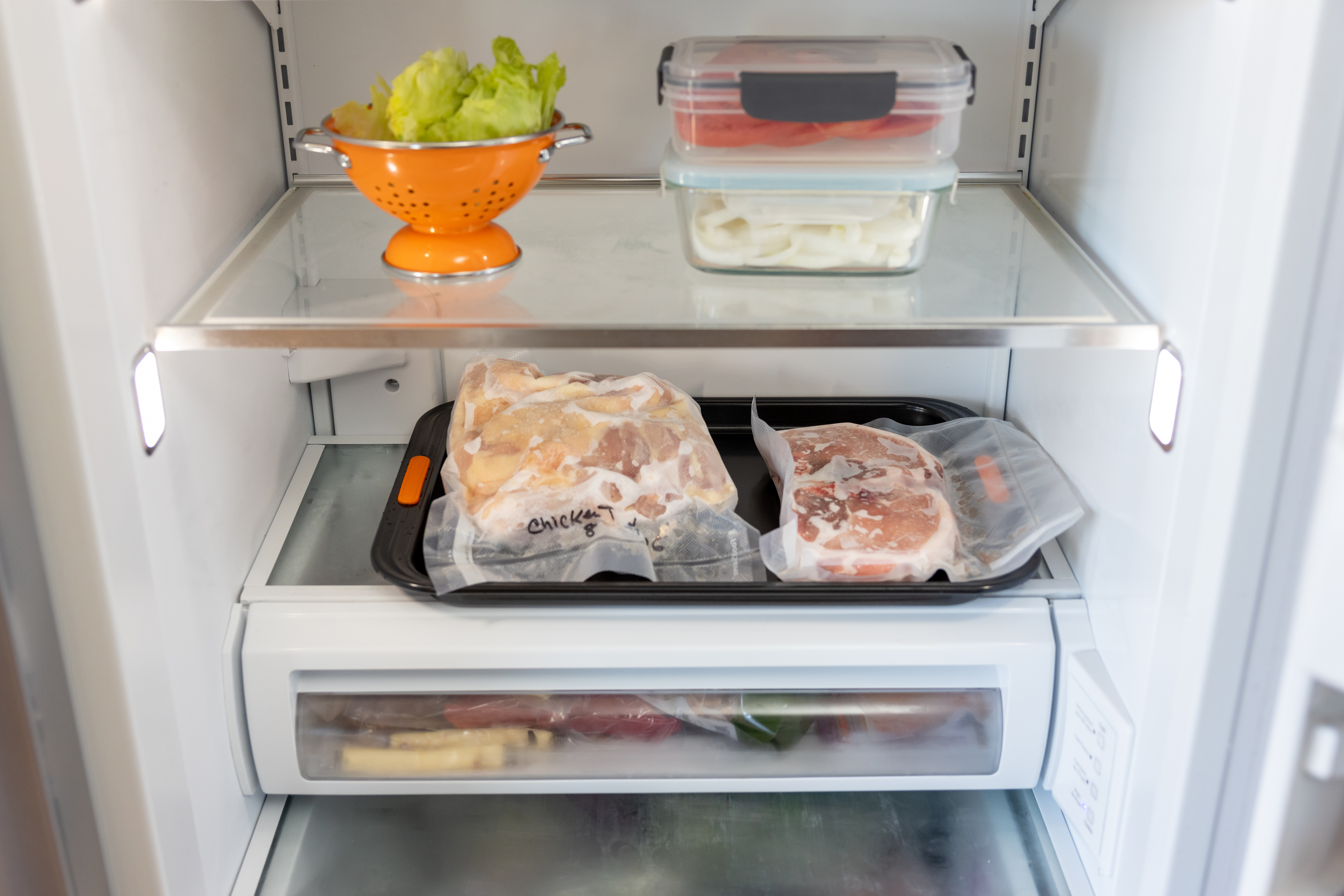 High quality stock photo of a African American man cooking hamburgers and chicken in his kitchen demonstrating food safety by separating meats from produces and keeping the area clean and washed.