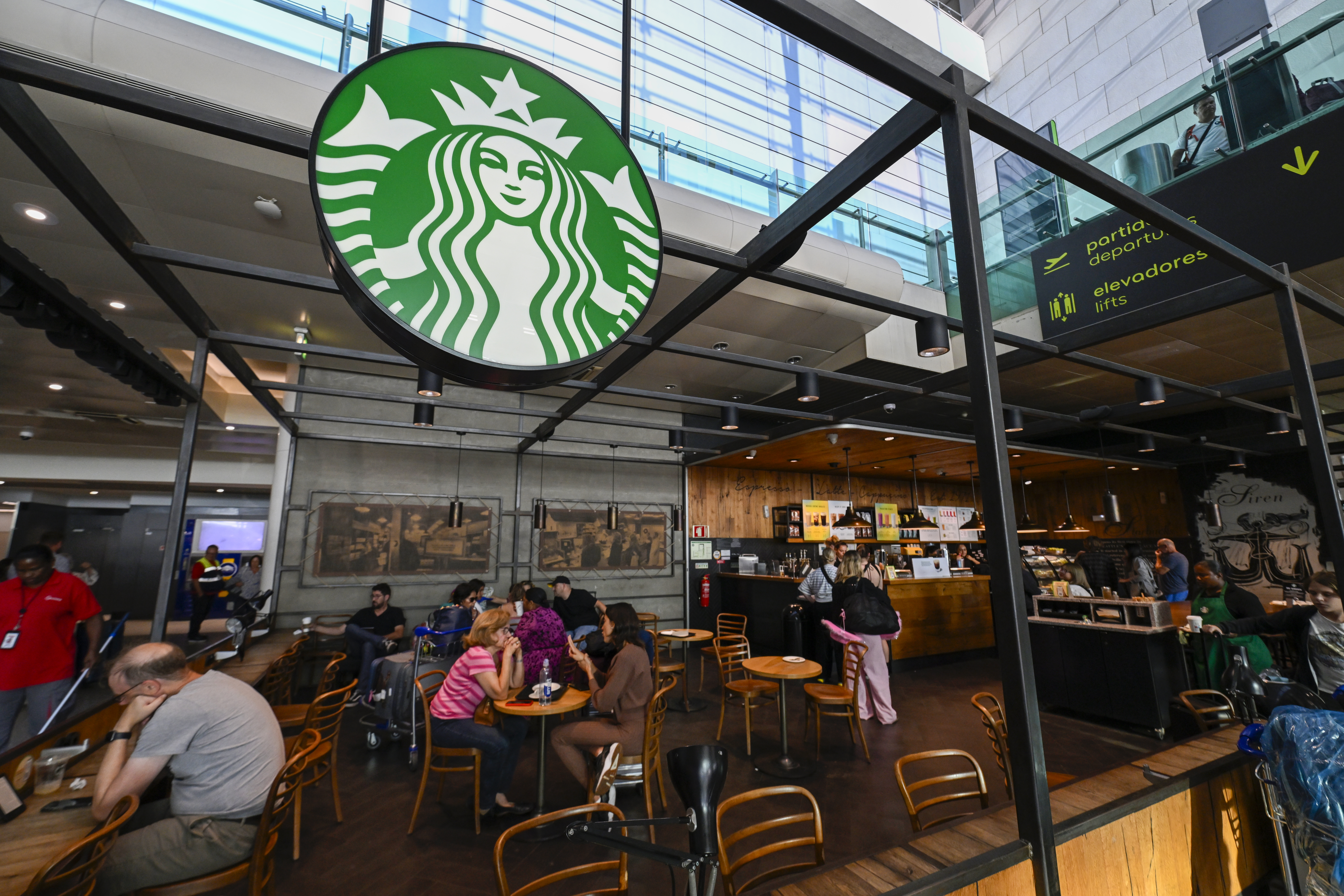 Los clientes se sientan en el café Starbucks en la sala de llegadas de la Terminal 1 del Aeropuerto Internacional Humberto Delgado el 2 de agosto de 2024