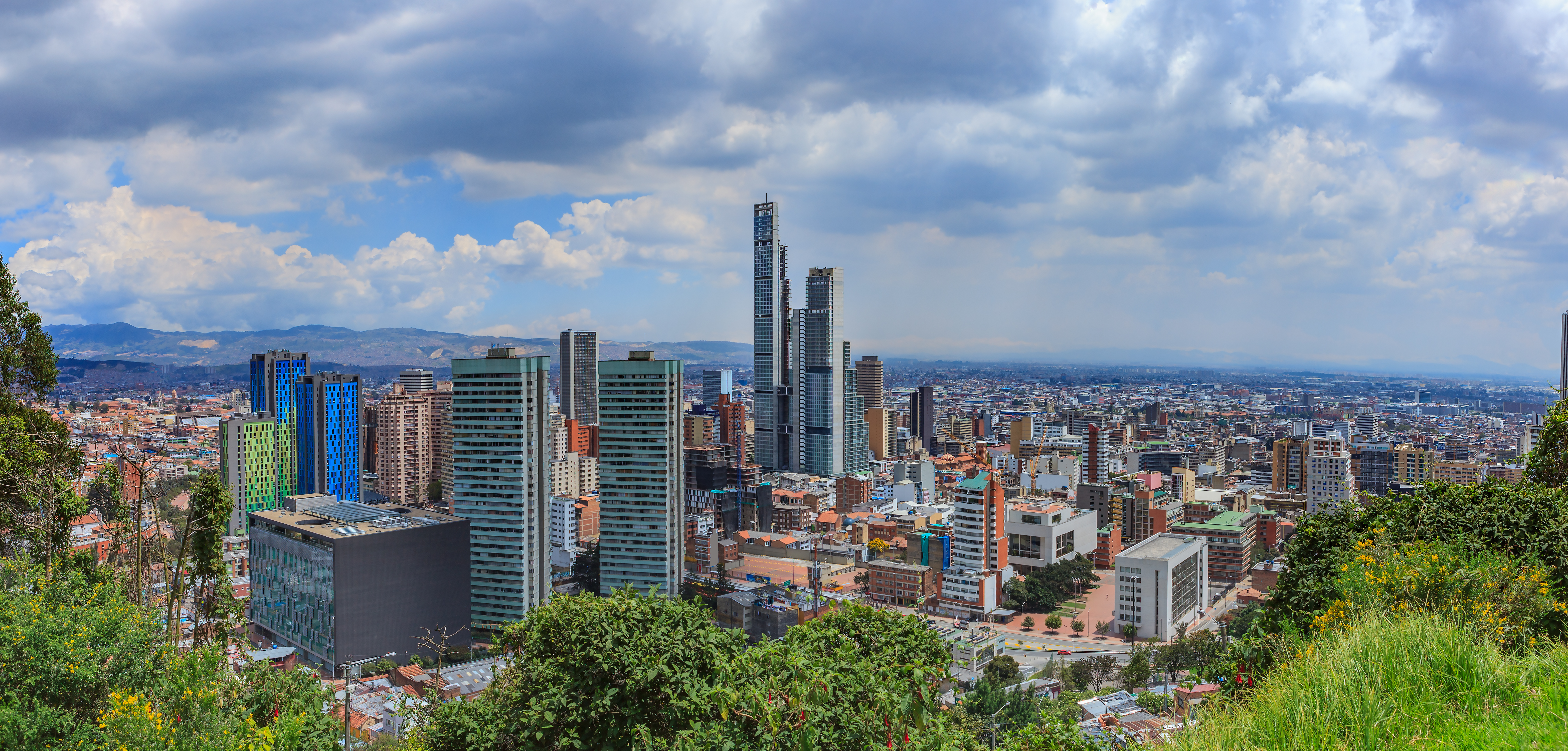 Bogotá, Colombia - Vista de ángulo alto del distrito del centro de la ciudad capital andina de Bogotá, Colombia en América del Sur. Al centro está el BD Bacatá, la estructura artificial más alta de Colombia. Ubicada a más de 8600 pies sobre el nivel medio del mar, con una población de casi 10 millones, Bogotá es una de las ciudades más grandes de América Latina. Foto tomada en la luz del sol de la mañana; panorama creado en Adobe Lightroom. La ubicación desde donde se tomó la imagen la convierte en una imagen poco común: no muchos fotógrafos se detendrán en la ubicación con una cara DSLR. El área se considera de alto riesgo de atraco e incluso apuñalamiento. Cámara: Canon EOS 5D MII. Objetivo: Canon EF 24-70 F2.8L USM.