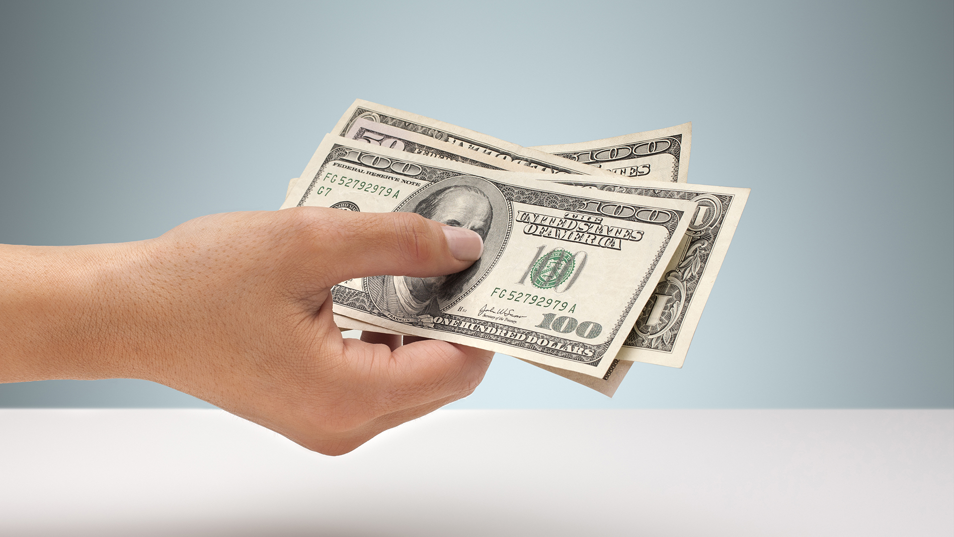 Mano sosteniendo una selección de billetes de dólar estadounidense