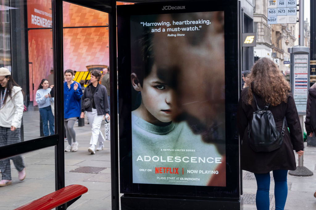 Passing people interacting with an advertising poster on a bus shelter for the Netflix drama 'Adolescence', the story of which is sparking conversations in public and govenrment around the subject of toxic masculinity and children's access to dangerous and misoginistic content on the internet and social media on 23rd March 2025 in London, United Kingdom. (photo by Mike Kemp/In Pictures via Getty Images)