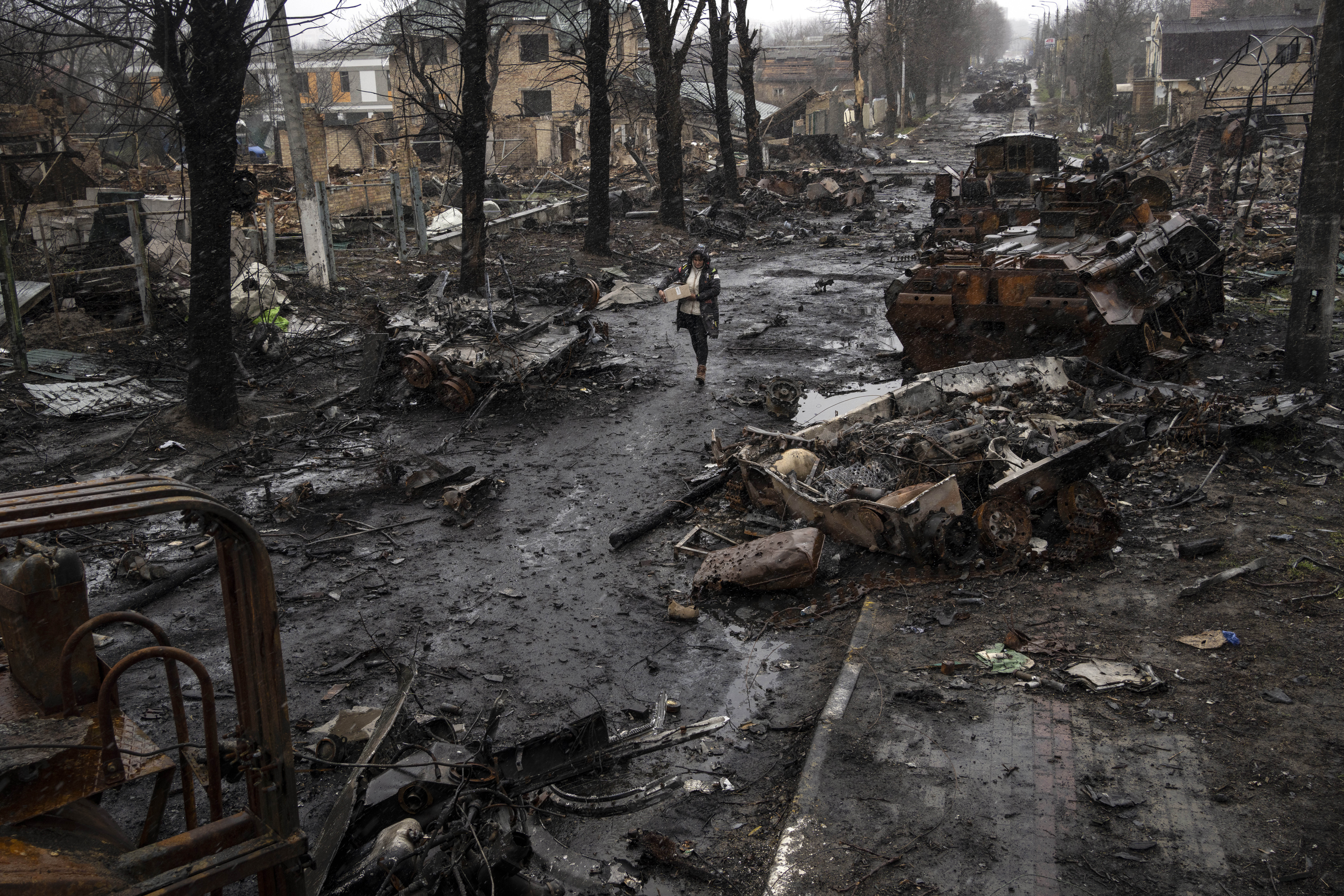 Una mujer camina entre tanques rusos destruidos en Bucha, en las afueras de Kiev, Ucrania, el domingo 3 de abril de 2022.