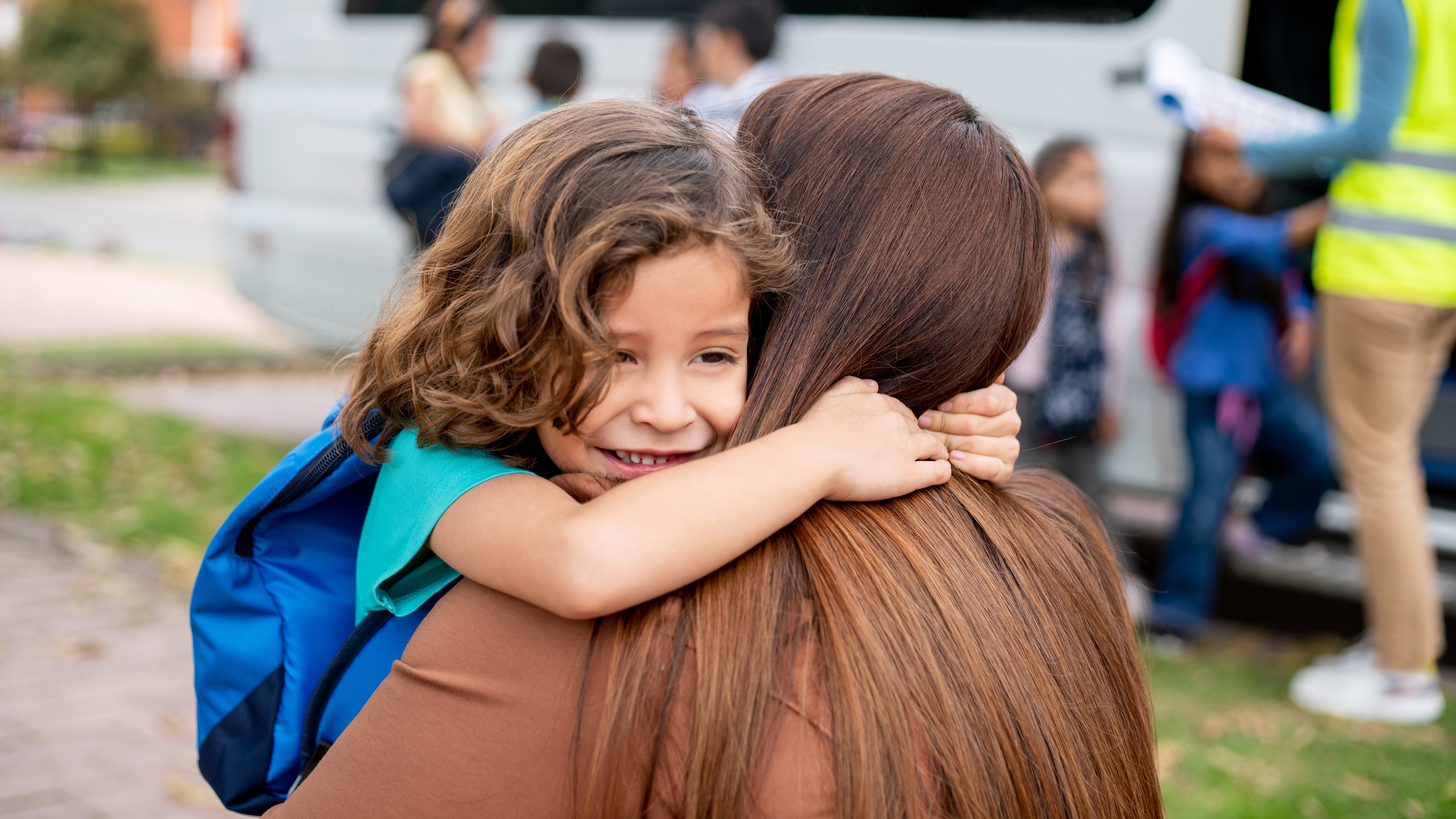 Latin American boy greeting his mother with a hug while she is picking him up from school - lifestyle concepts