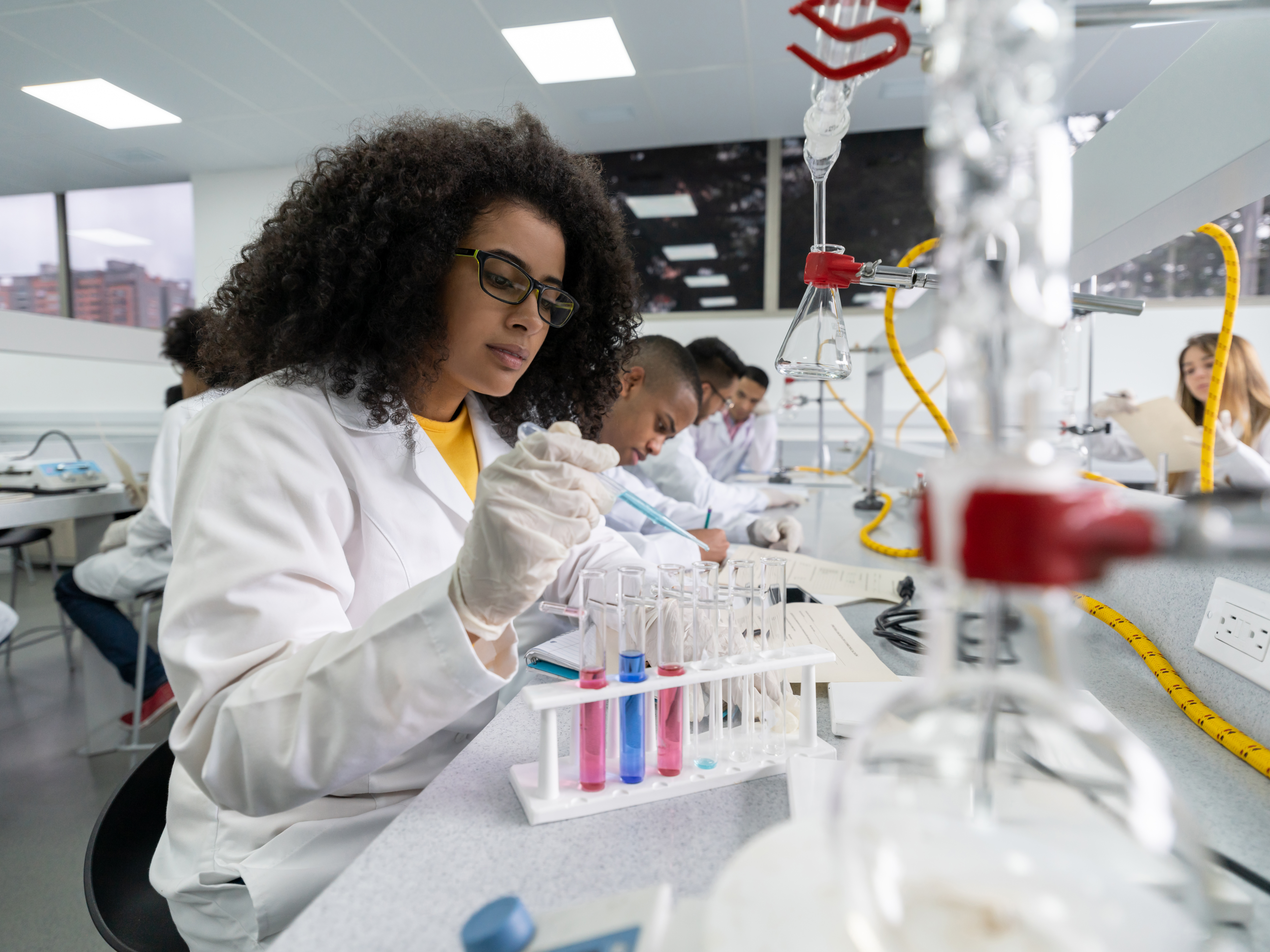 African American woman in a science class making experiments at the lab using test tubes and pipets