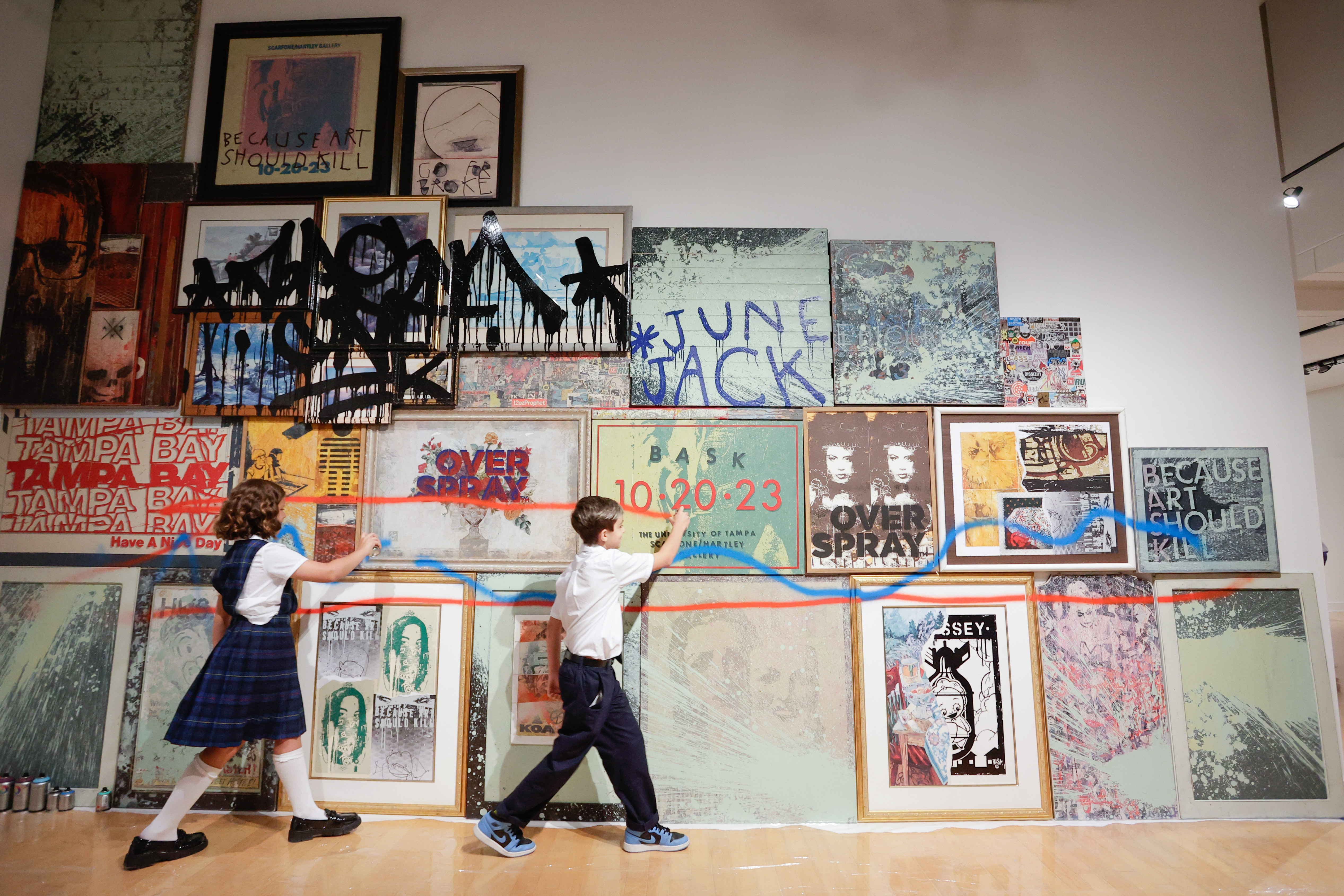 June Gahhos, 9, and Jack Gerow-Vitale, 9, spray-paint a section of art from local artist Ales Bask Hostomsky during the opening reception to his newest show “B.A.S.K.: Because Art Should Kill” on Friday, Oct. 20, 2023, in Tampa.