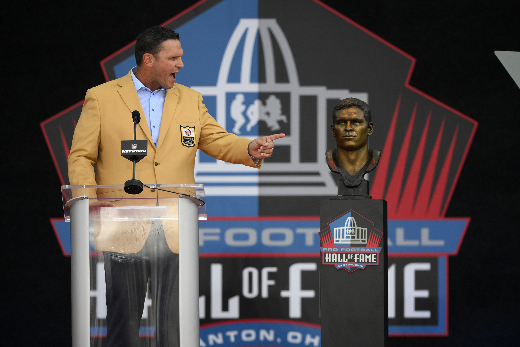 Former NFL player Bryant Young poses with his bust during an