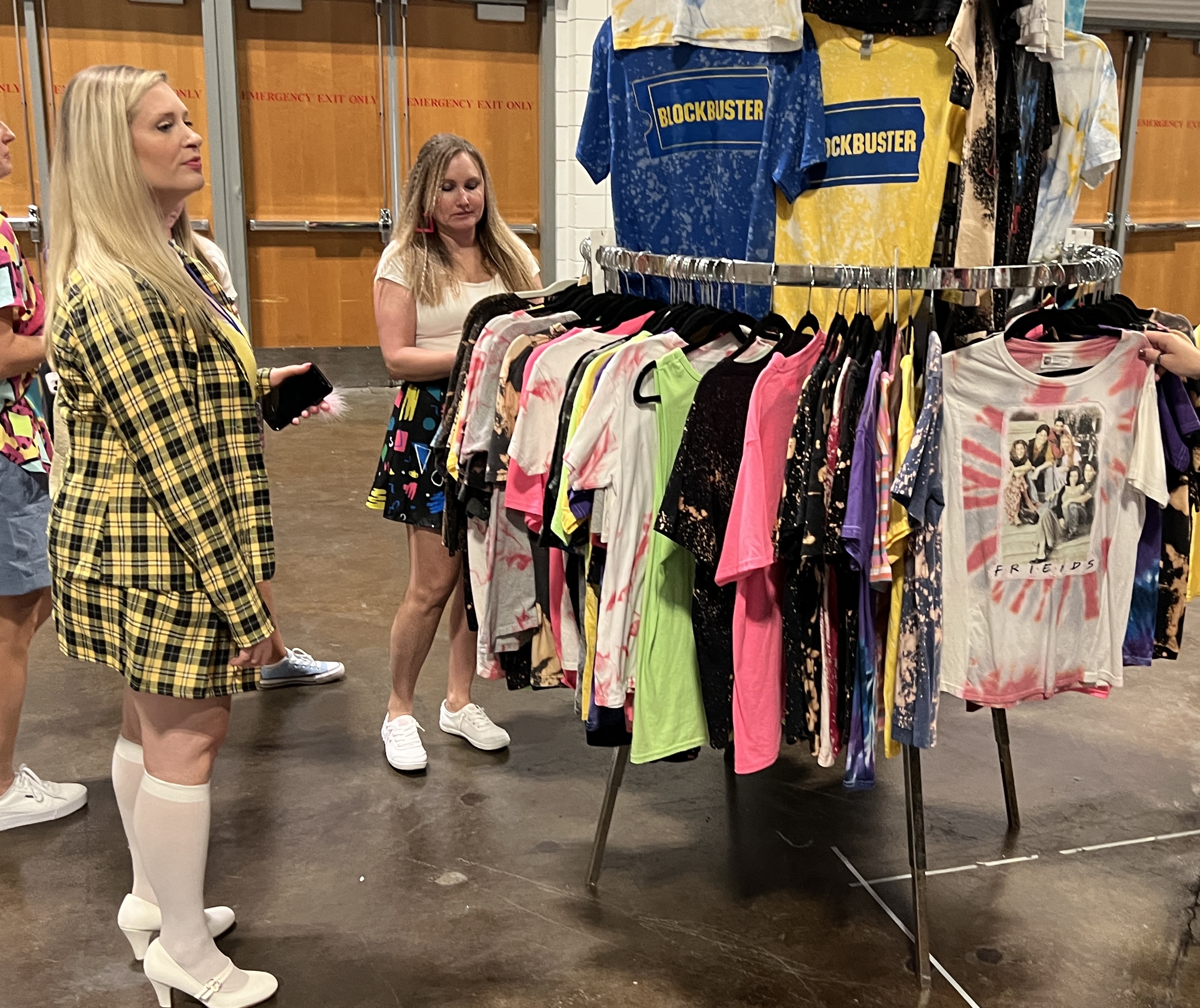 Jenny Albano, 37, of Tampa, left, peruses a rack of 1990s-themed T-shirts during the 90s Con event at Tampa Convention Center on Sunday, Sept. 17, 2023. Albano came to the convention dressed as Cher from "Clueless."