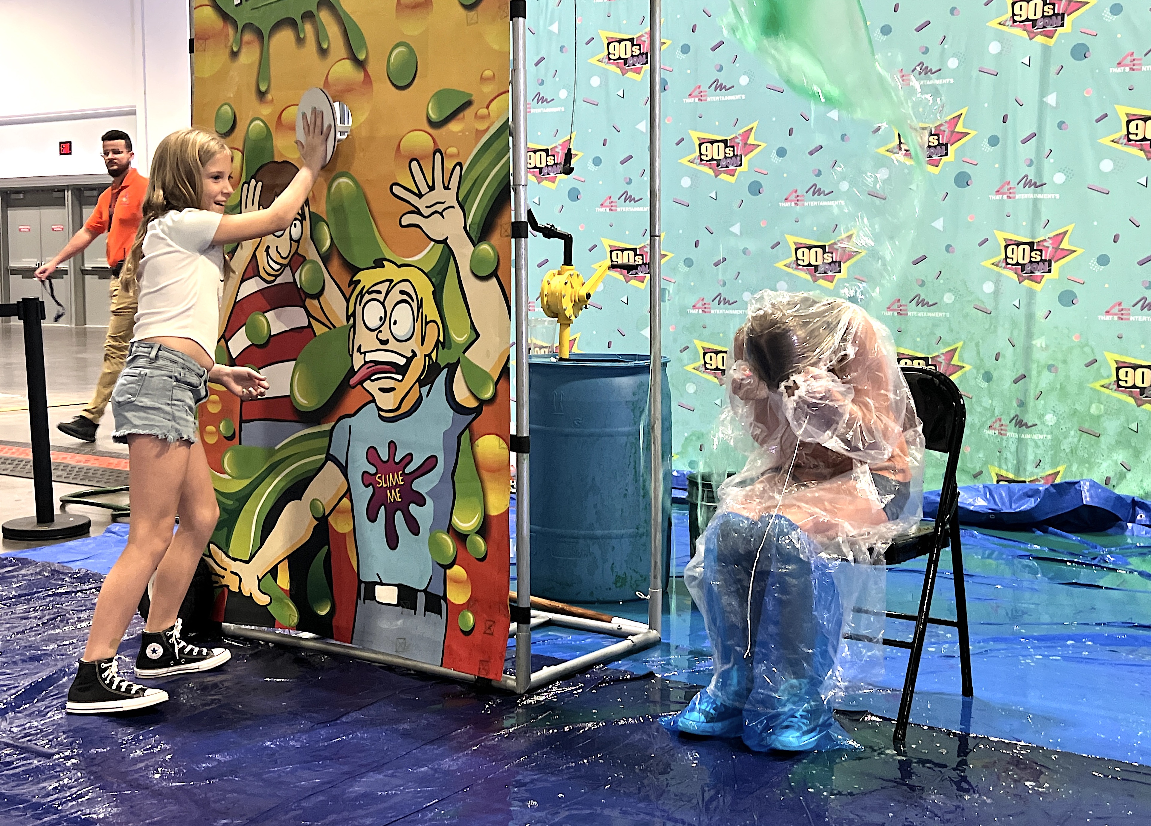 Rylan Townsend, 9, presses a button to drop "slime" on her sister Raegan Townsend, 11, during 90s Con at the Tampa Convention Center on Sunday, Sept. 17, 2023.