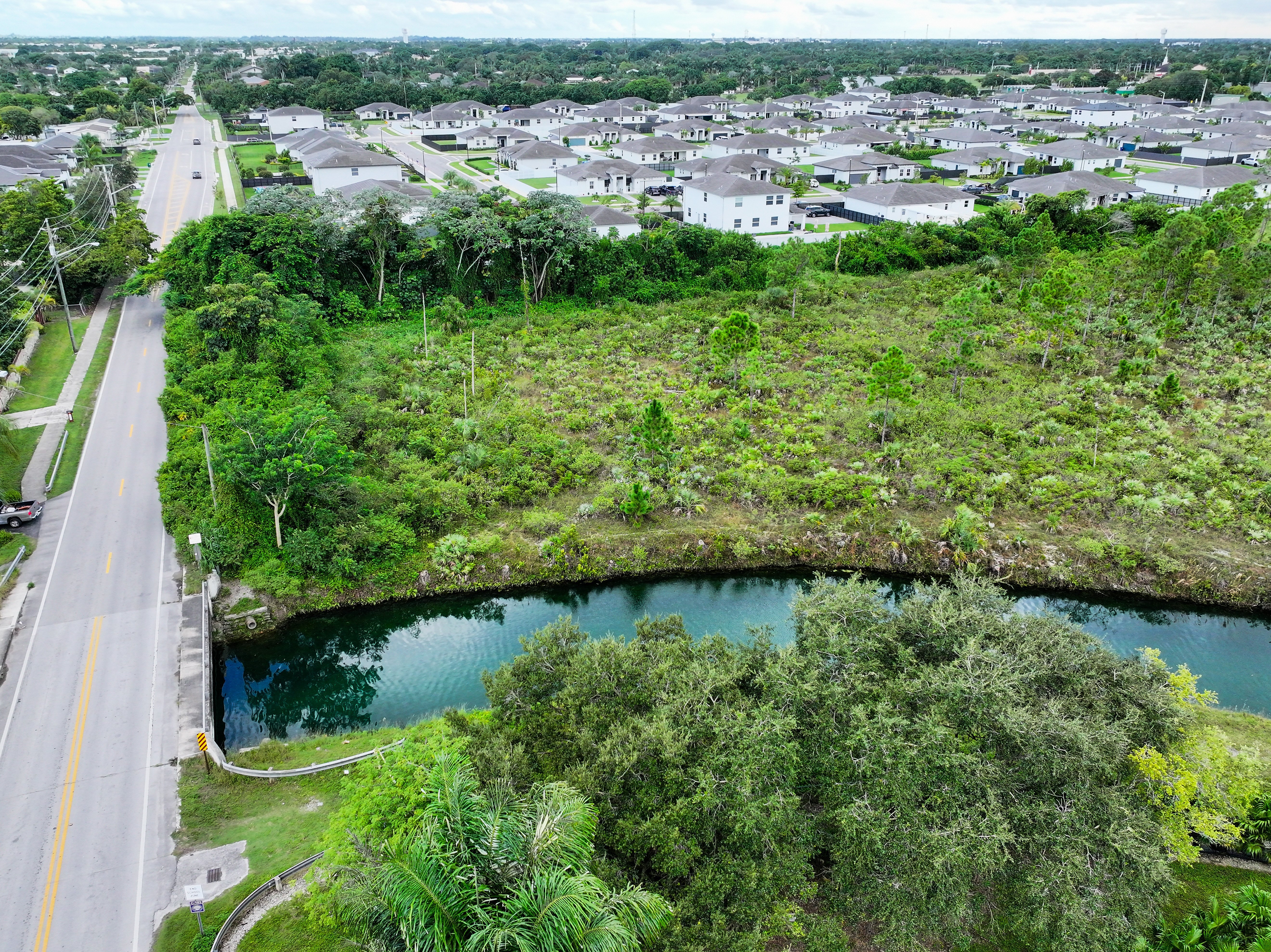 A drone image shows rows of houses near a canal in Homestead in South Florida. When it rains, the pollution from urban runoff drains into Biscayne Bay.

