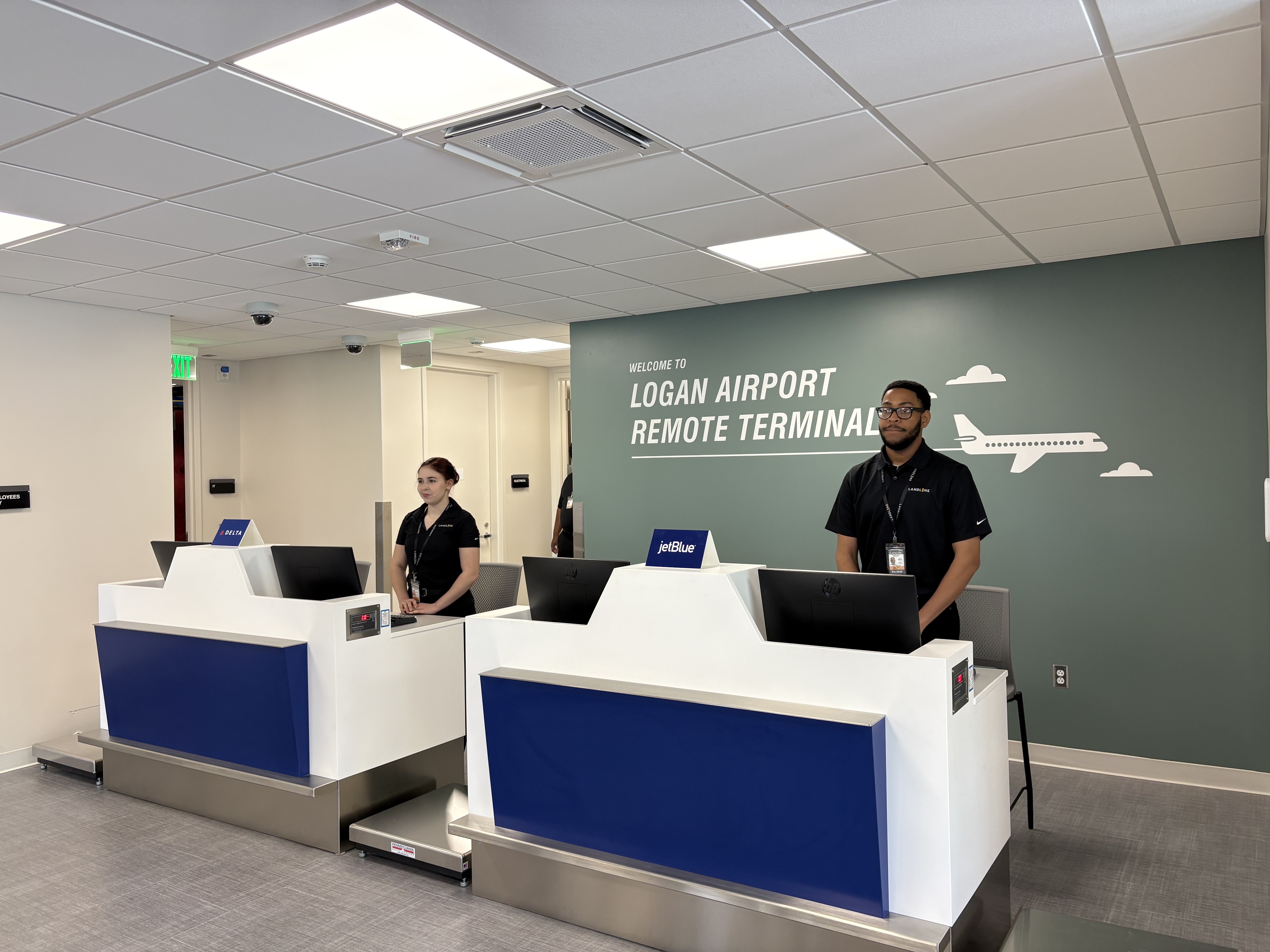 Customer representatives with Landline wait at the airline check-in desks at Boston Logan International Airport’s remote terminal. (Andrea Sachs/The Washington Post)