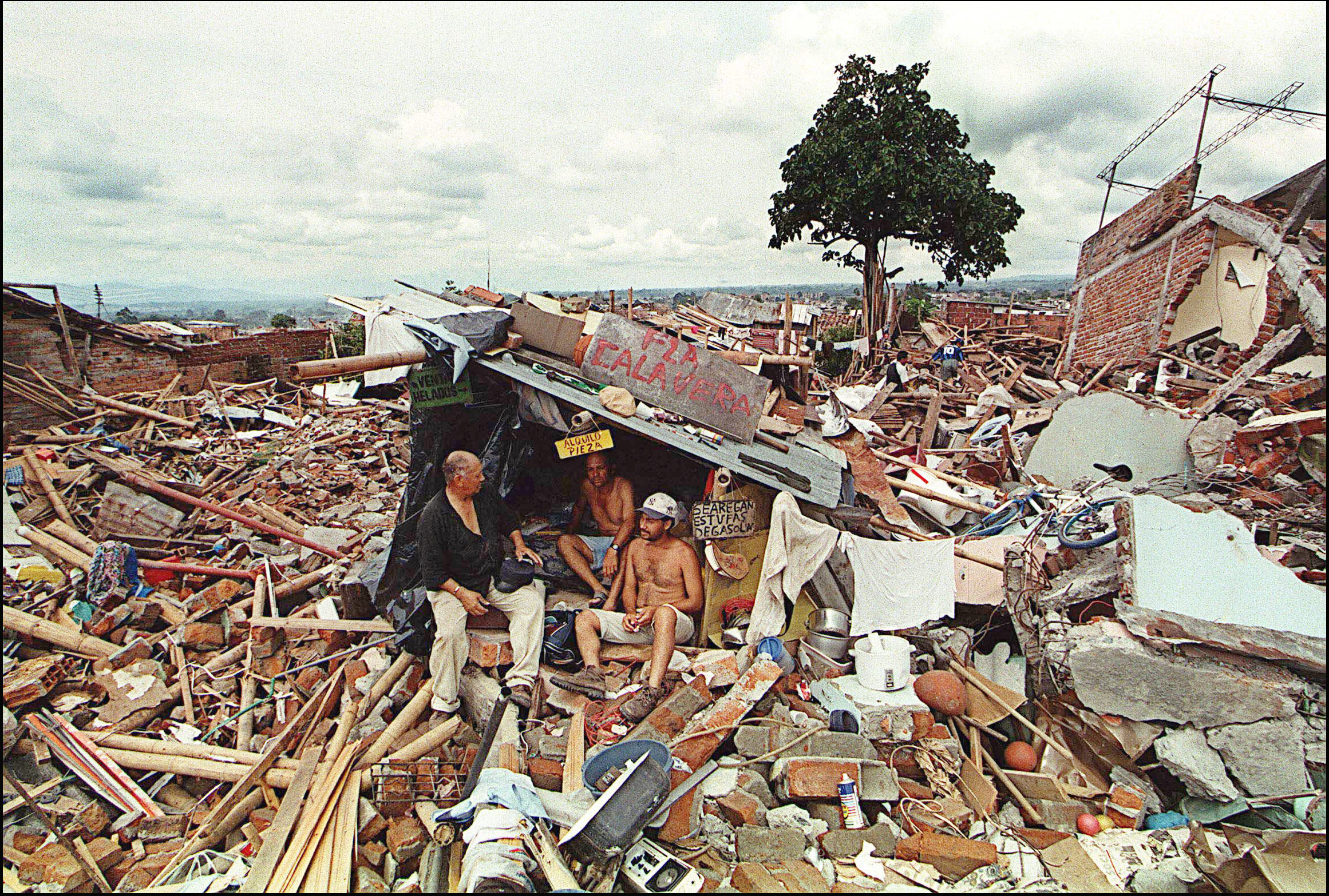 Victims of a 6.2-magnitude earthquake that rocked the Colombian city of Armenia and the surrounding area in January 1999 shelter under a makeshift structure amid the rubble one week after the disaster. (Marcelo Salinas/AFP/Getty Images)