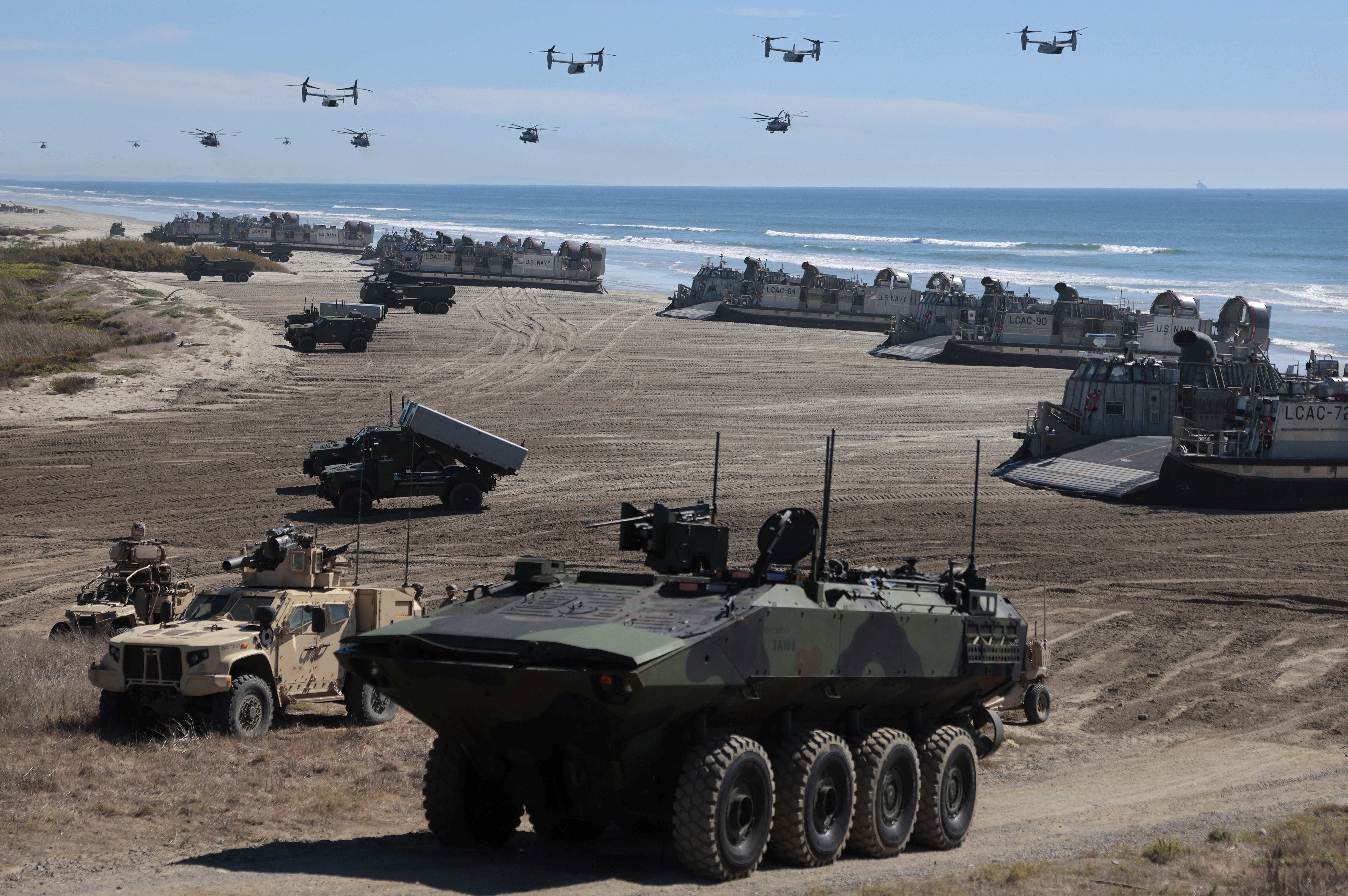 Navy Landing Craft Air Cushions unload equipment onto the beach at Camp Pendleton in Oceanside, California, last year as U.S. Marine Corps V-22 Ospreys and CH-53 Super Stallions fly overhead during an event commemorating the 250th birthday of the U.S. Marine Corps. (Mario Tama/Getty Images)