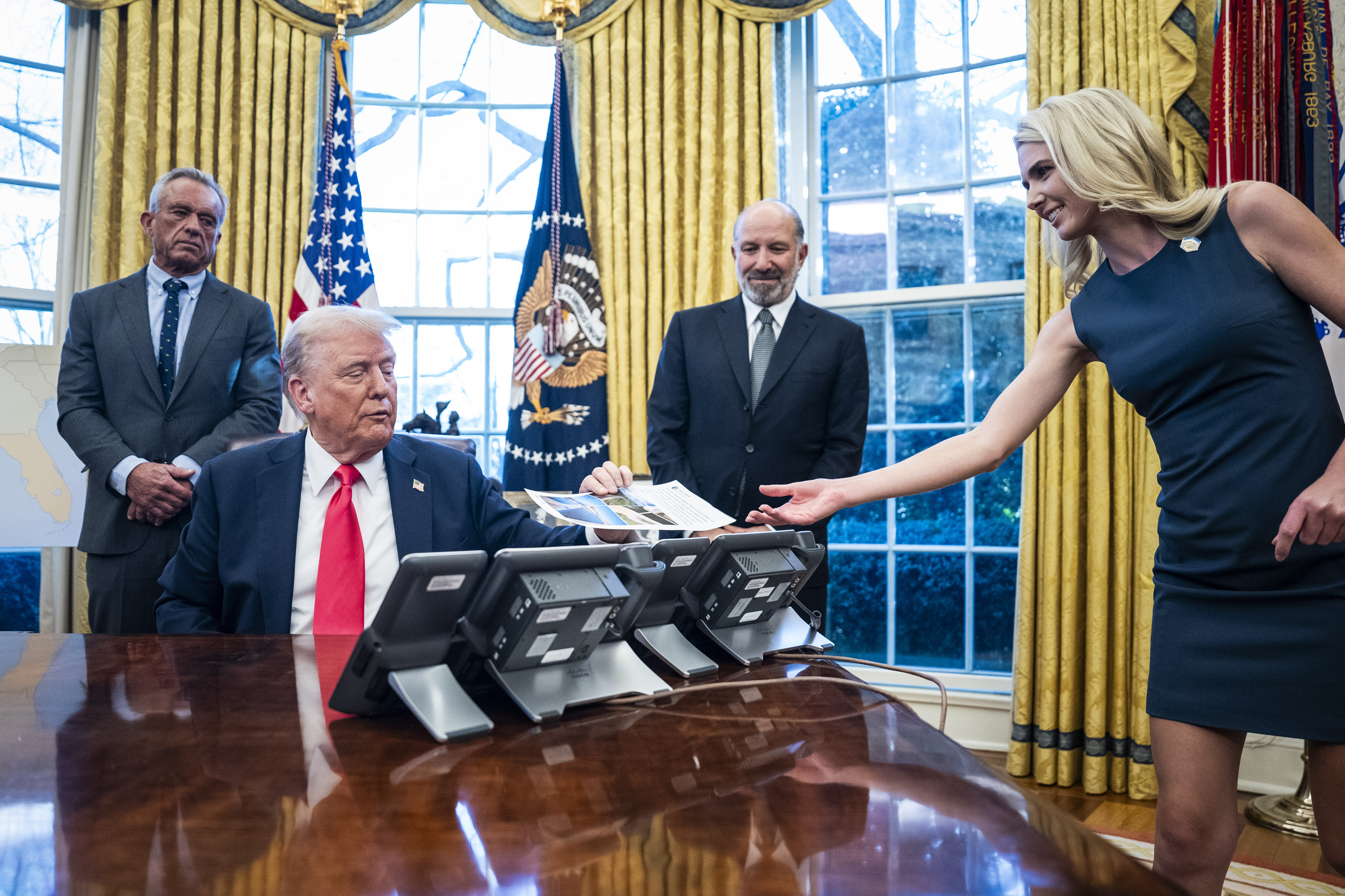Harp hands Trump a printout in the Oval Office in February 2025. (Jabin Botsford/The Washington Post)