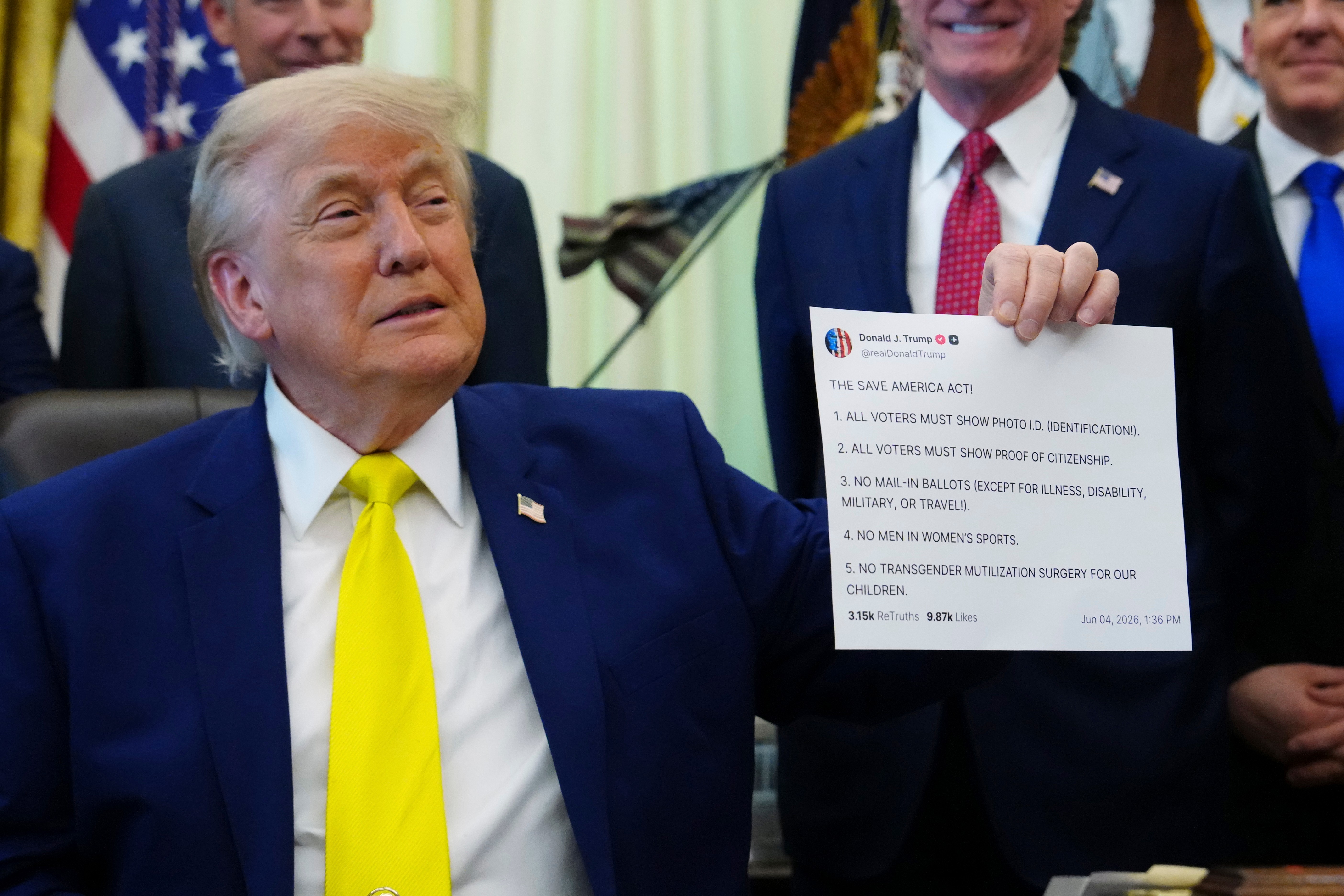 President Donald Trump holds up a print-out of one of his Truth Social posts at an Oval Office event in June. (Julia Demaree Nikhinson/AP)