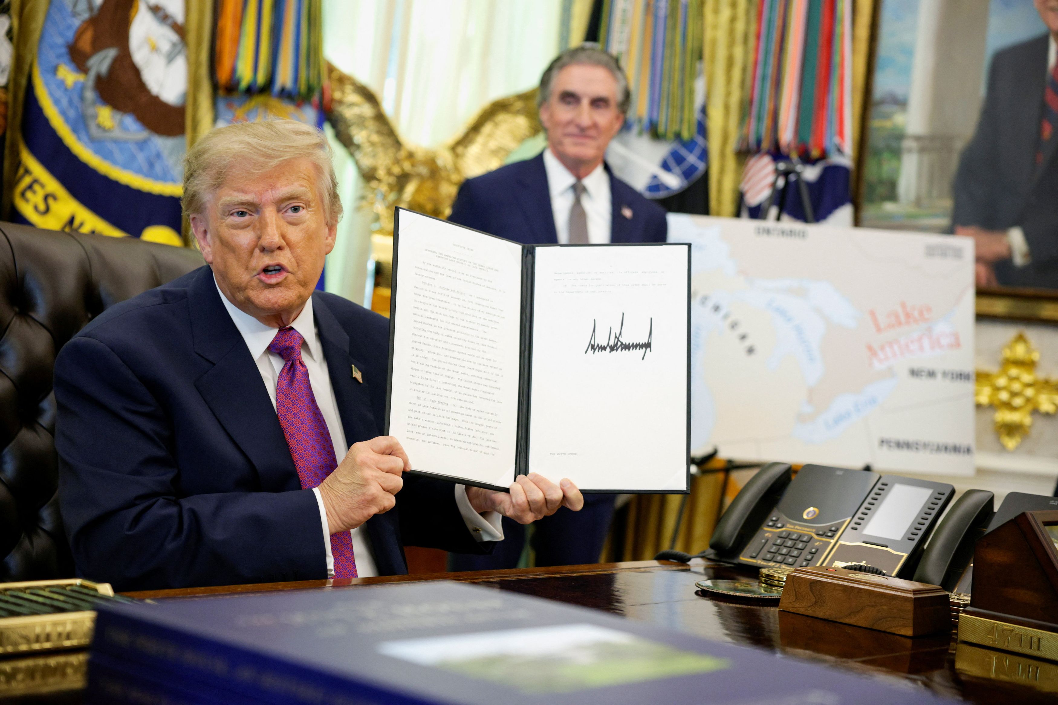 President Donald Trump holds the executive order Thursday renaming Lake Ontario as Lake America. (Evan Vucci/Reuters)