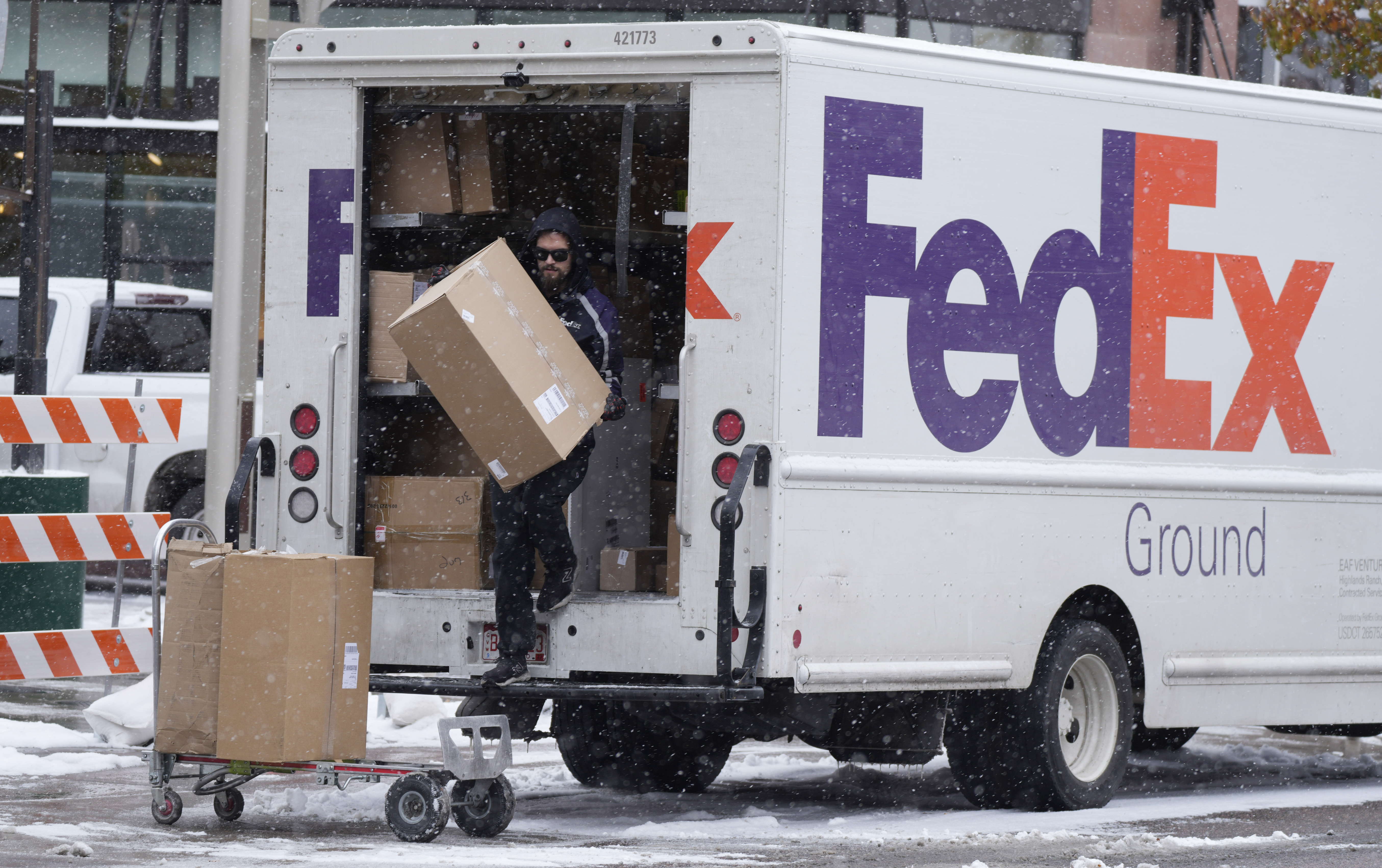 A FedEx delivery person carries a package from a truck in Denver. (David Zalubowski/AP)