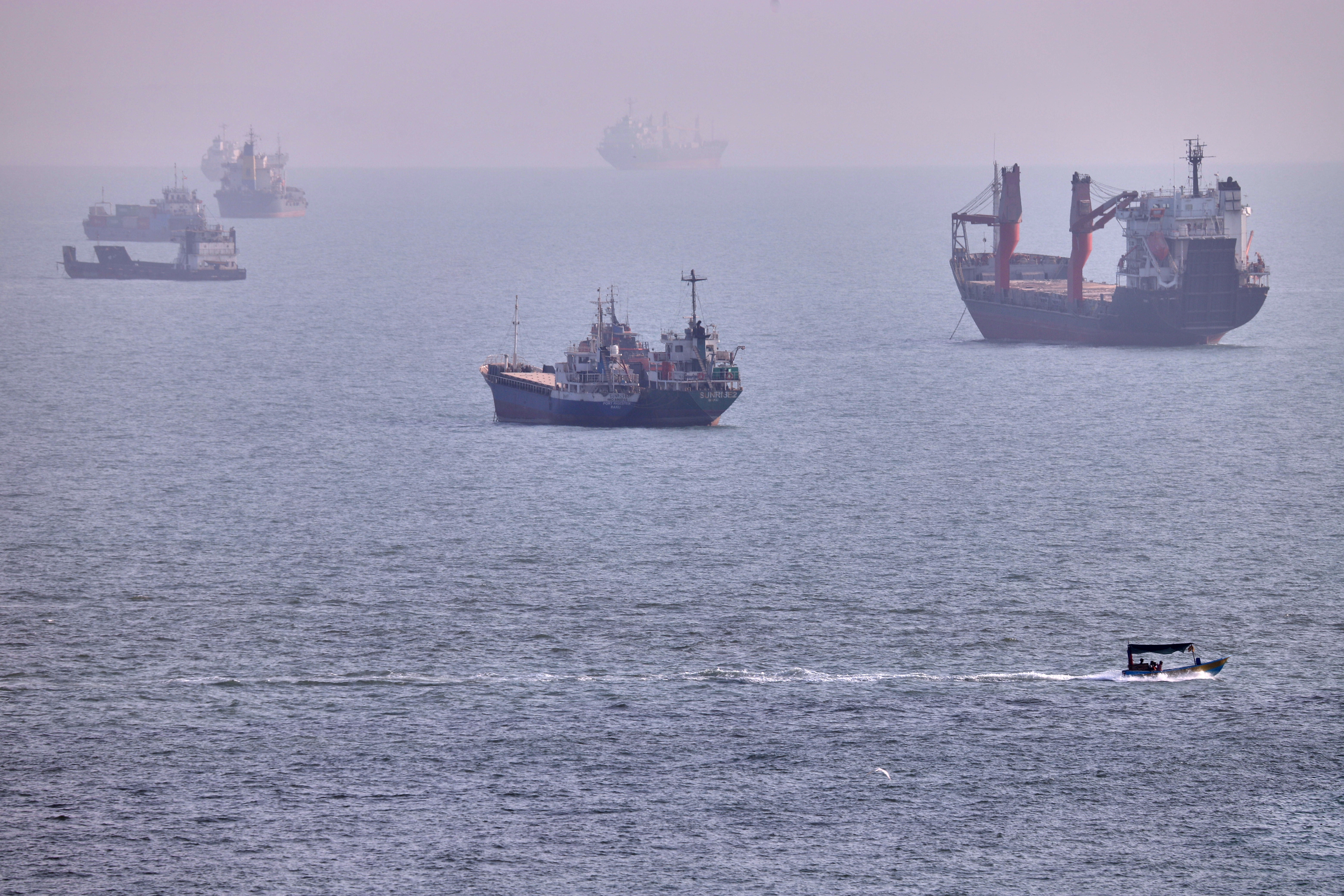 A small boat moves past vessels anchored in the Strait of Hormuz off Bandar Abbas, Iran, on Wednesday. (Amirhosein Khorgooi/ISNA/AP)