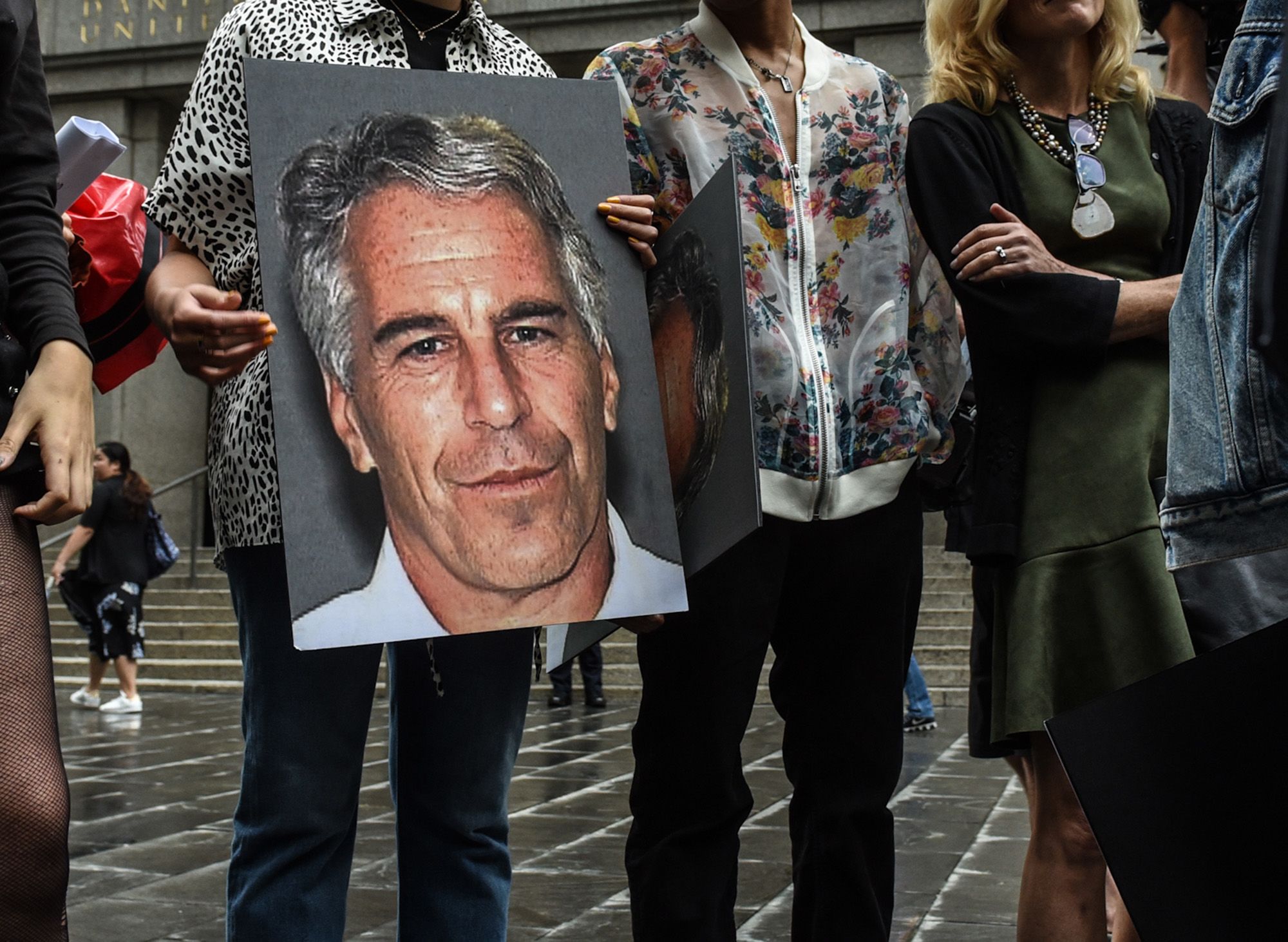 Protesters hold up signs with images of disgraced financier and convicted sex offender Jeffrey Epstein in front of the federal courthouse in New York in 2019. (Stephanie Keith/Getty Images)