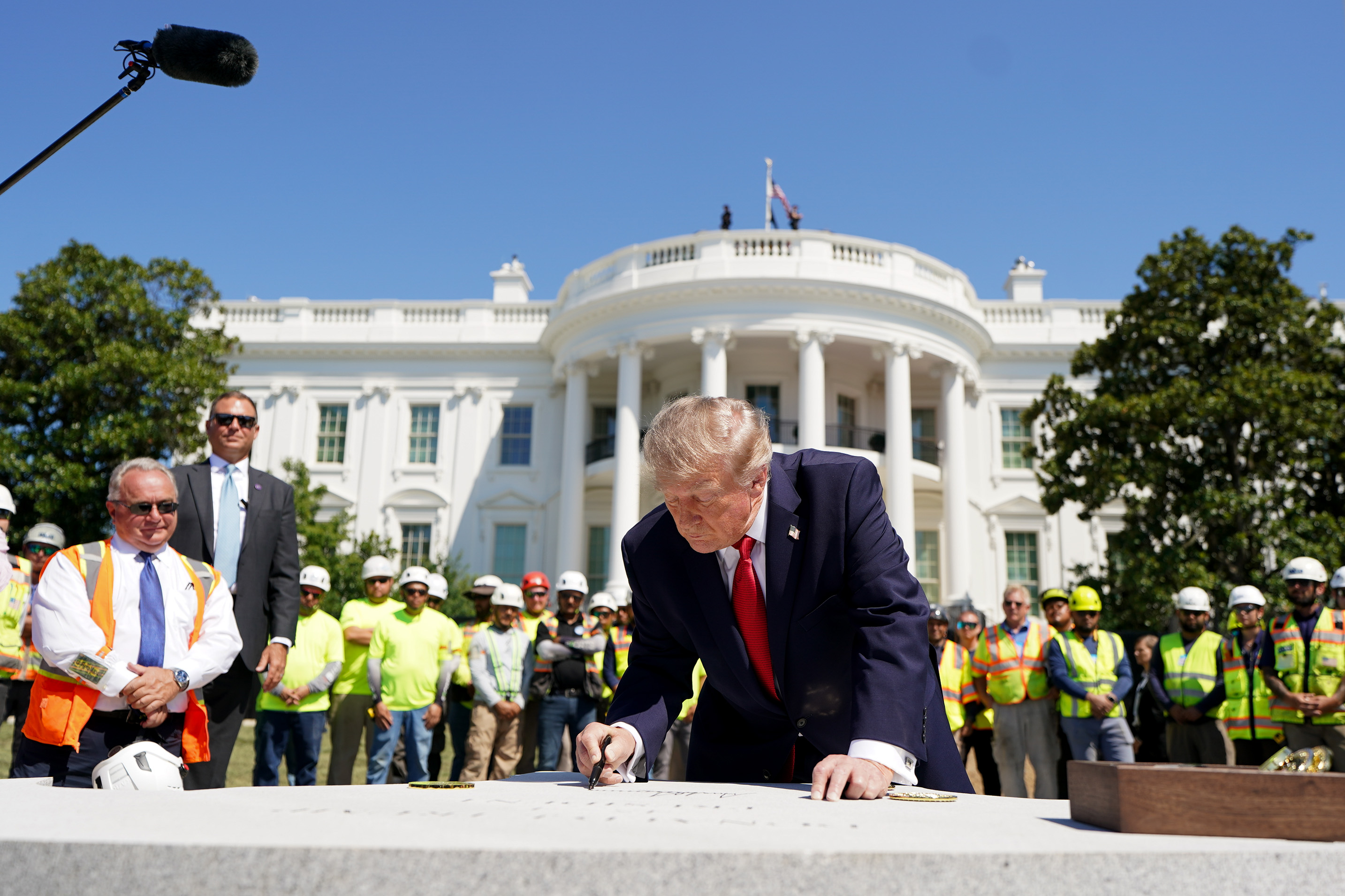Trump signs a piece of stone as he tours the construction. (Al Drago/Pool/For The Washington Post)