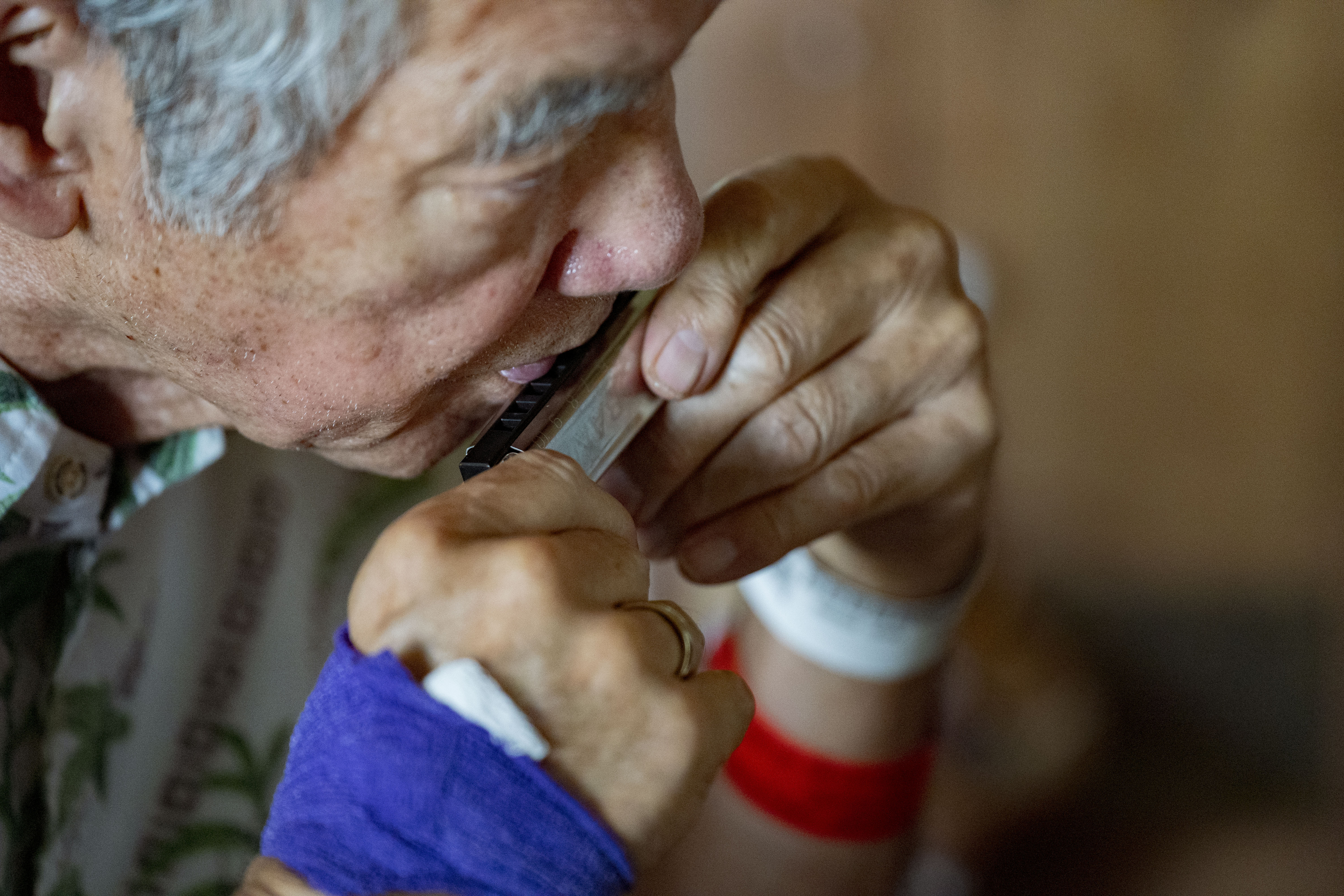 Neal Tomita, 79, plays the harmonica during a virtual class for people with Parkinson’s disease and their care partners. (Mengshin Lin/For The Washington Post)