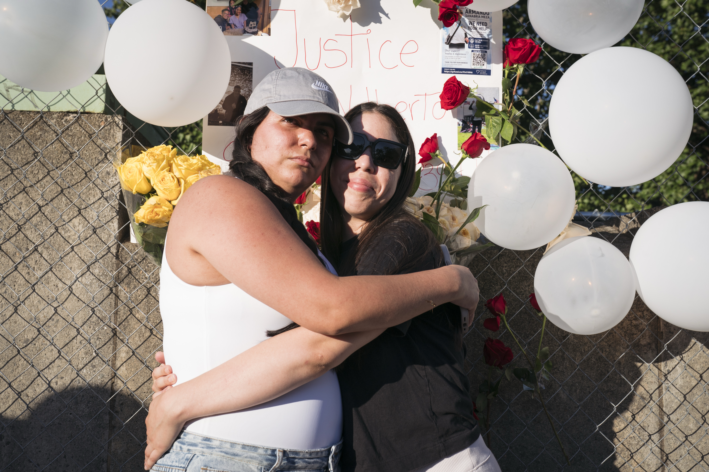 María Laura Ines Martínez Cespedes, left, and Verónica Andrea Sanabria Cespedes comfort each other at the shrine for their uncle at D.C.'s William Howard Taft Bridge on Wednesday. Nolberto Armando Sanabria Meza was killed last Saturday when his moped was hit by a car being pursued by police in a high-speed chase. (Maxine Wallace/The Washington Post)