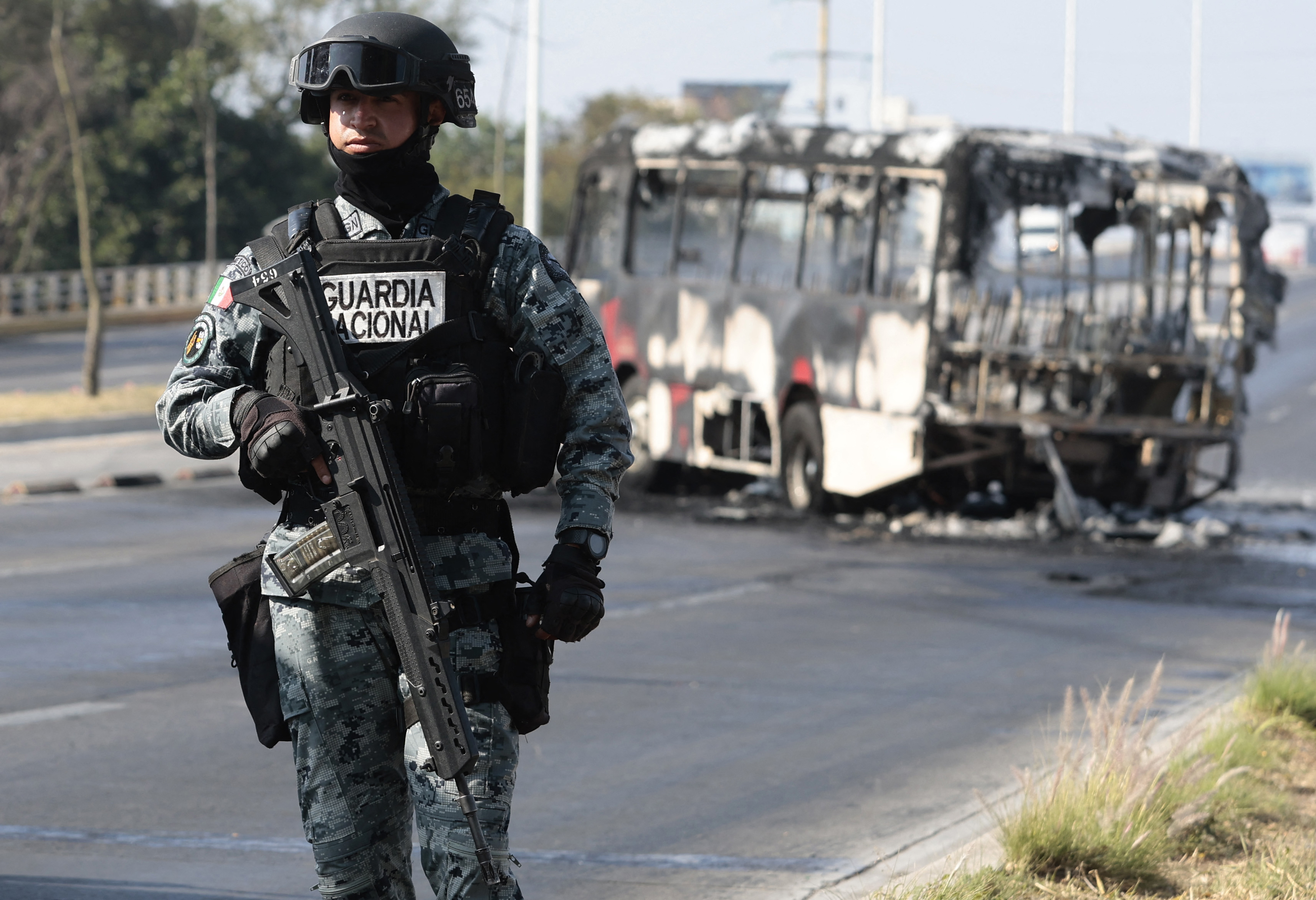 A member of Mexico's national guard stands near a burned bus Sunday in Zapopan, in Jalisco state, amid unrest there. (Ulises Ruiz/AFP/Getty Images)