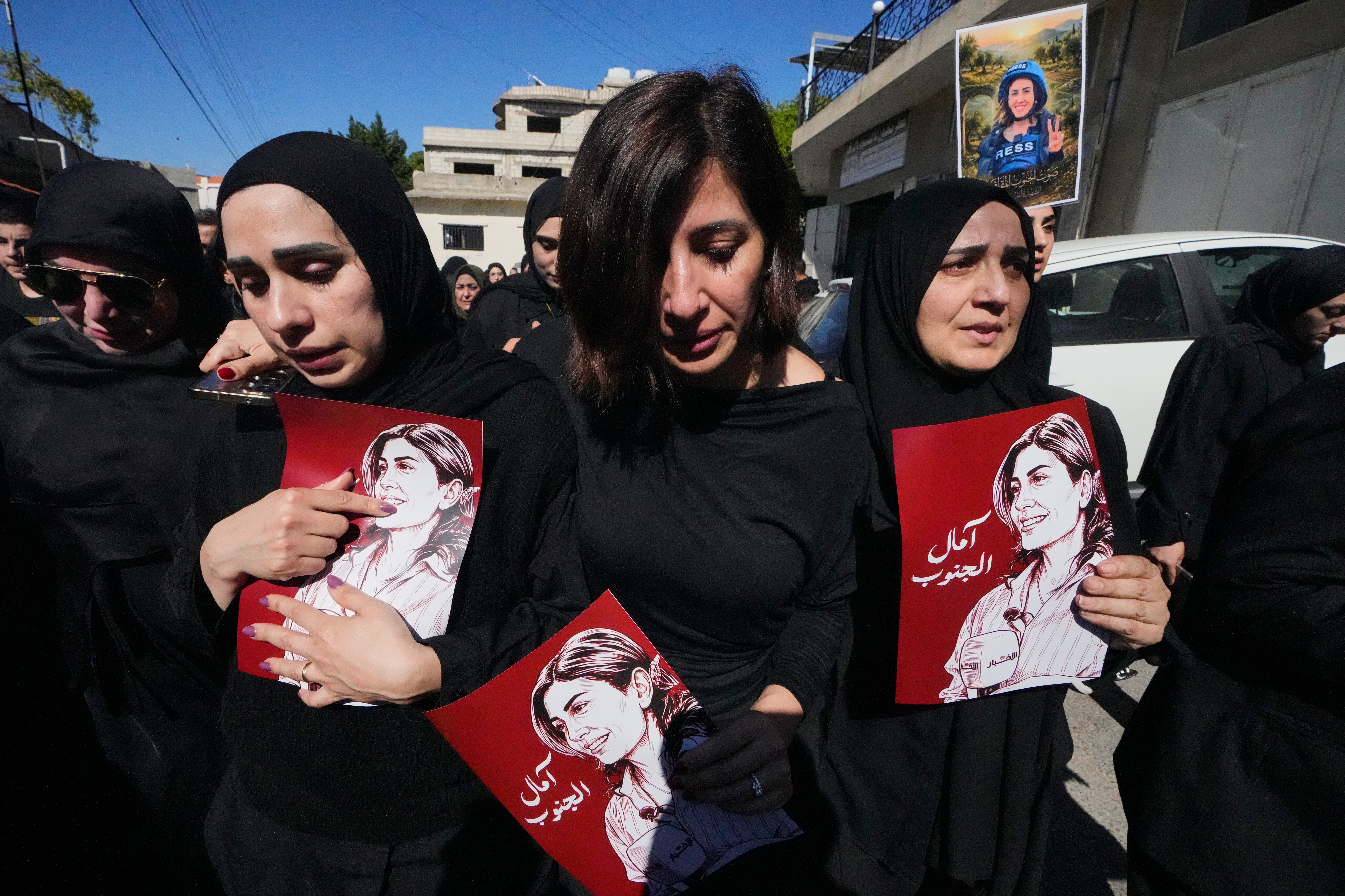 Mourners hold posters that show portraits of Lebanese journalist Amal Khalil, who was killed in an Israeli airstrike. (Mohammed Zaatari/AP)